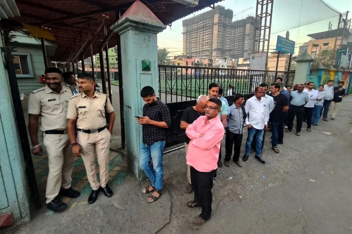 Police personnel stand guard as people wait in a queue to cast votes during the Navi Mumbai Municipal Corporation (NMMC) elections, at a polling station (Photo:PTI)