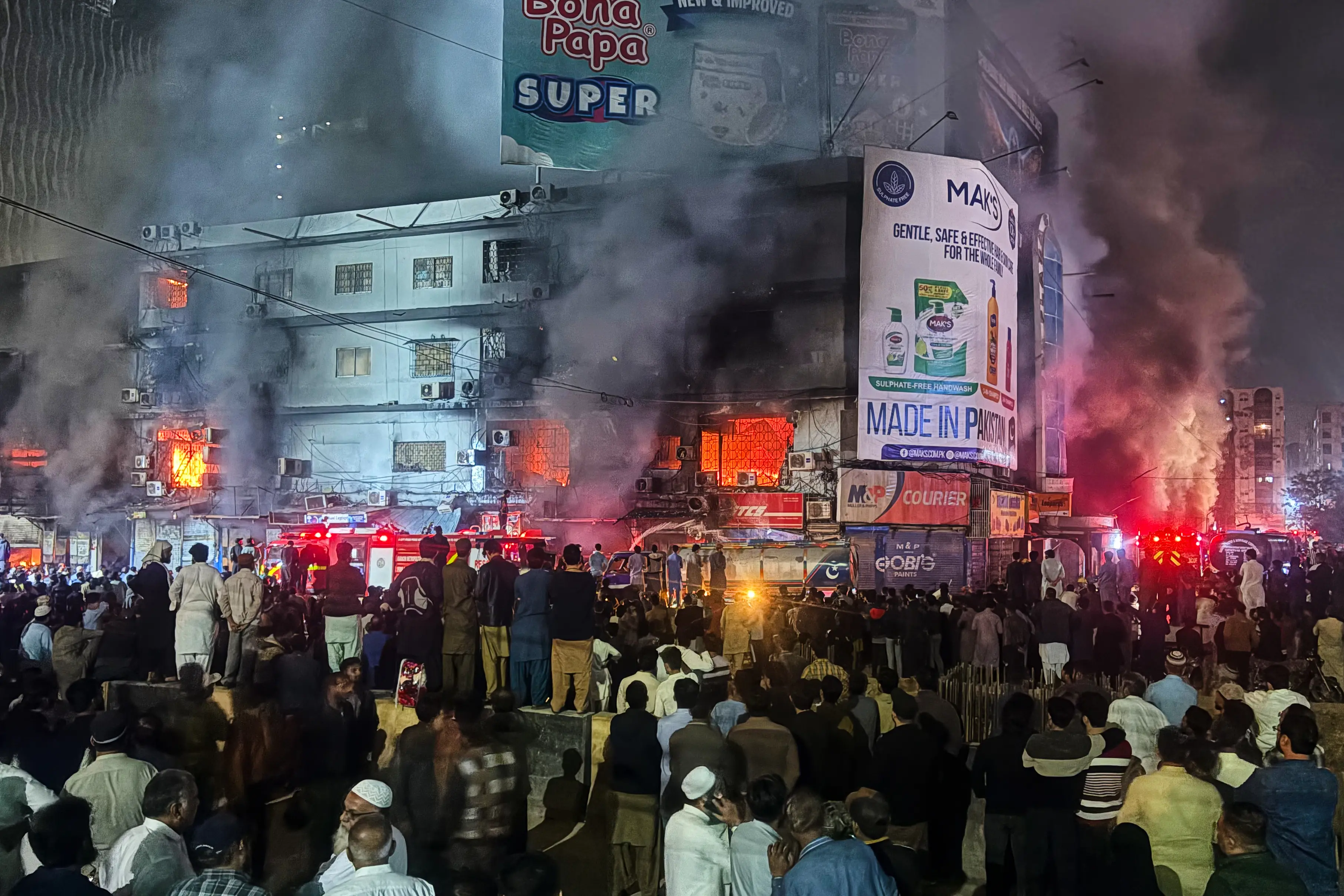 People gather as firefighters try to control a massive fire that broke out in a multi-story shopping mall, in Karachi | Photo: AP