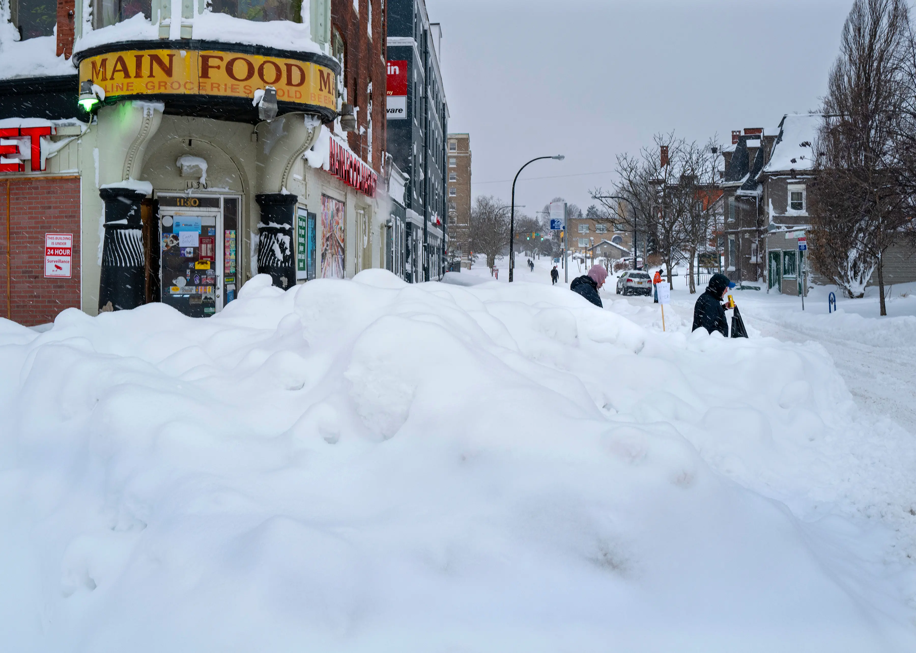 People walk from a grocery store in Buffalo, NY, after a massive snow storm blanketed the city.| Photo: AP