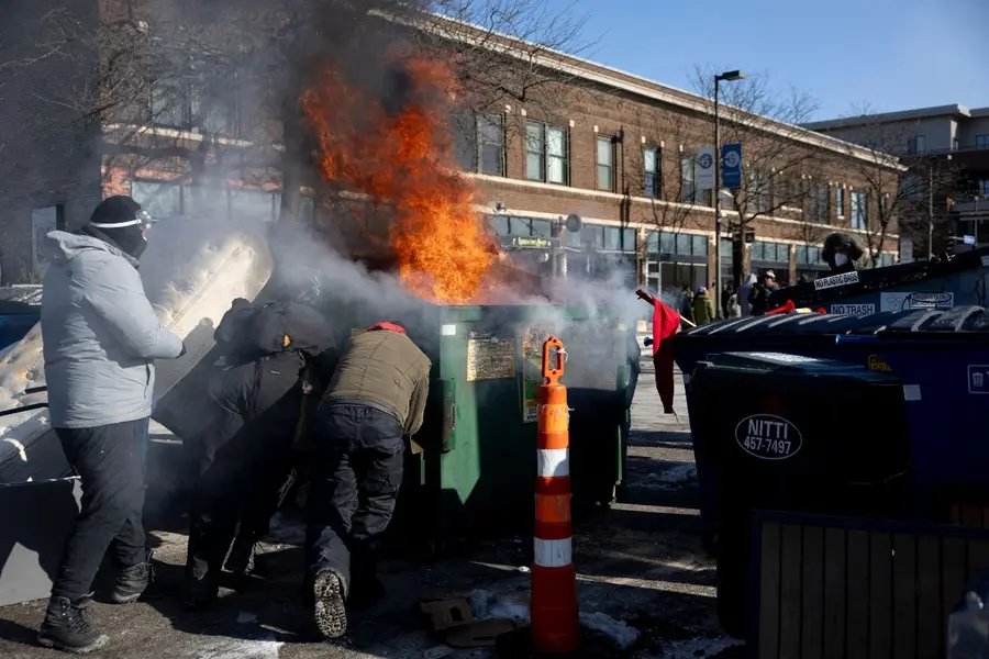 Protesters push an a burning dumpster toward law enforcement near the site of the fatal shooting of 37-year-old Alex Pretti by federal agents in Minneapolis on Saturday