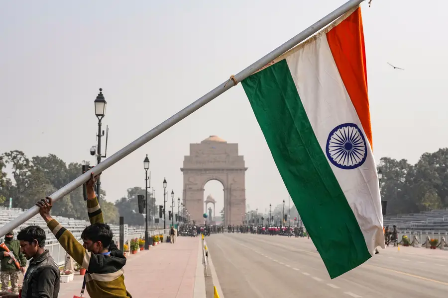 Workers raise a pole bearing the Indian national flag during rehearsals for the Republic Day Parade, near the India Gate