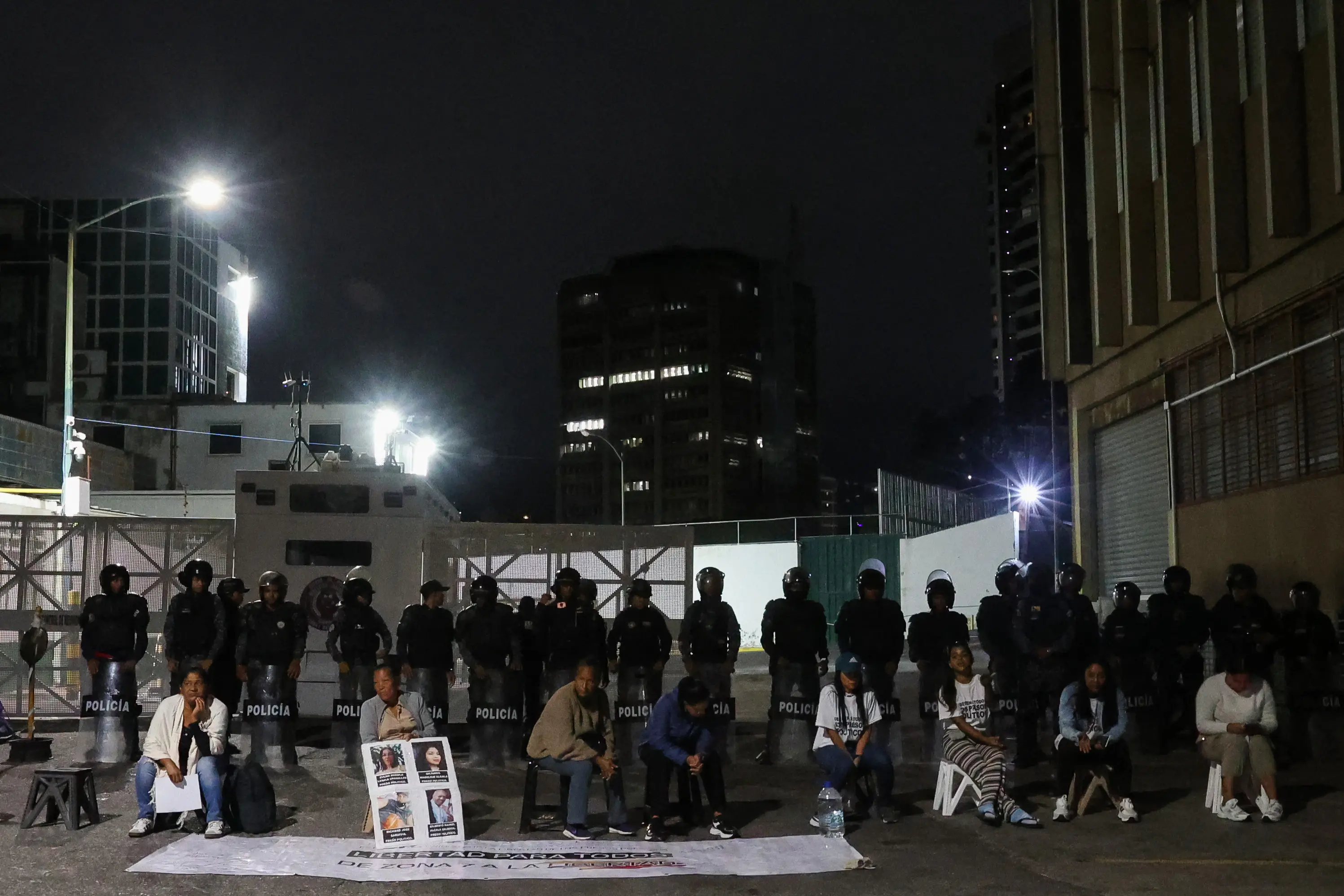 Women wait for news about the release of prisoners in front of members of the national police standing guard outside Zone 7 of the Bolivarian National Police (PNB) in the Sucre municipality of the Metropolitan District of Caracas (DMC) on January 26. More than 100 political prisoners were freed on the eve in Venezuela | Photo: AFP