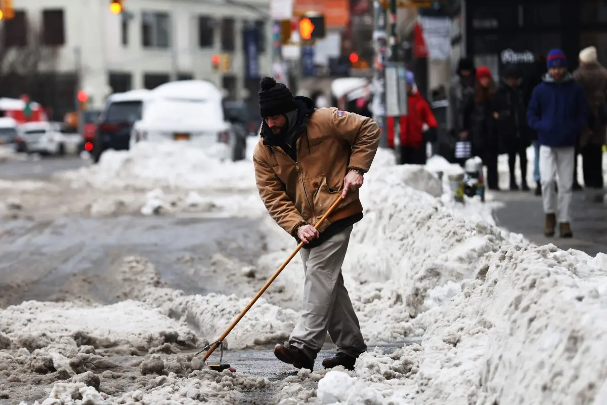 A man shovels snow in Manhattan after a storm left nearly one foot of snow on January 26, 2026 in New York City.| Photo: AFP