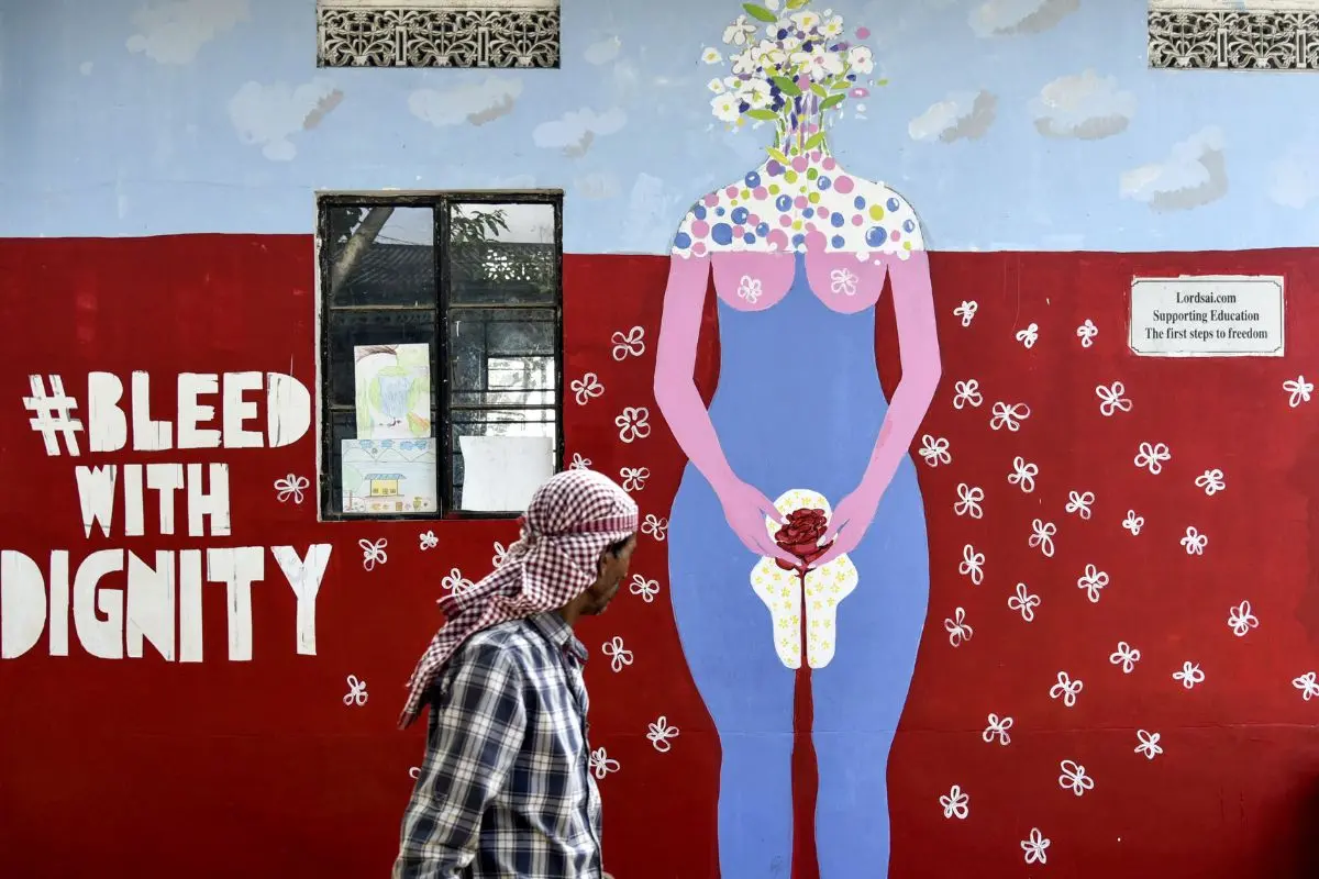 An Indian man looks on as he walks along a wall painting about female menstruation at the school for underprivileged children, Parijat Academy, on the Menstrual Hygiene Day in Guwahati. | File Photo: AFP