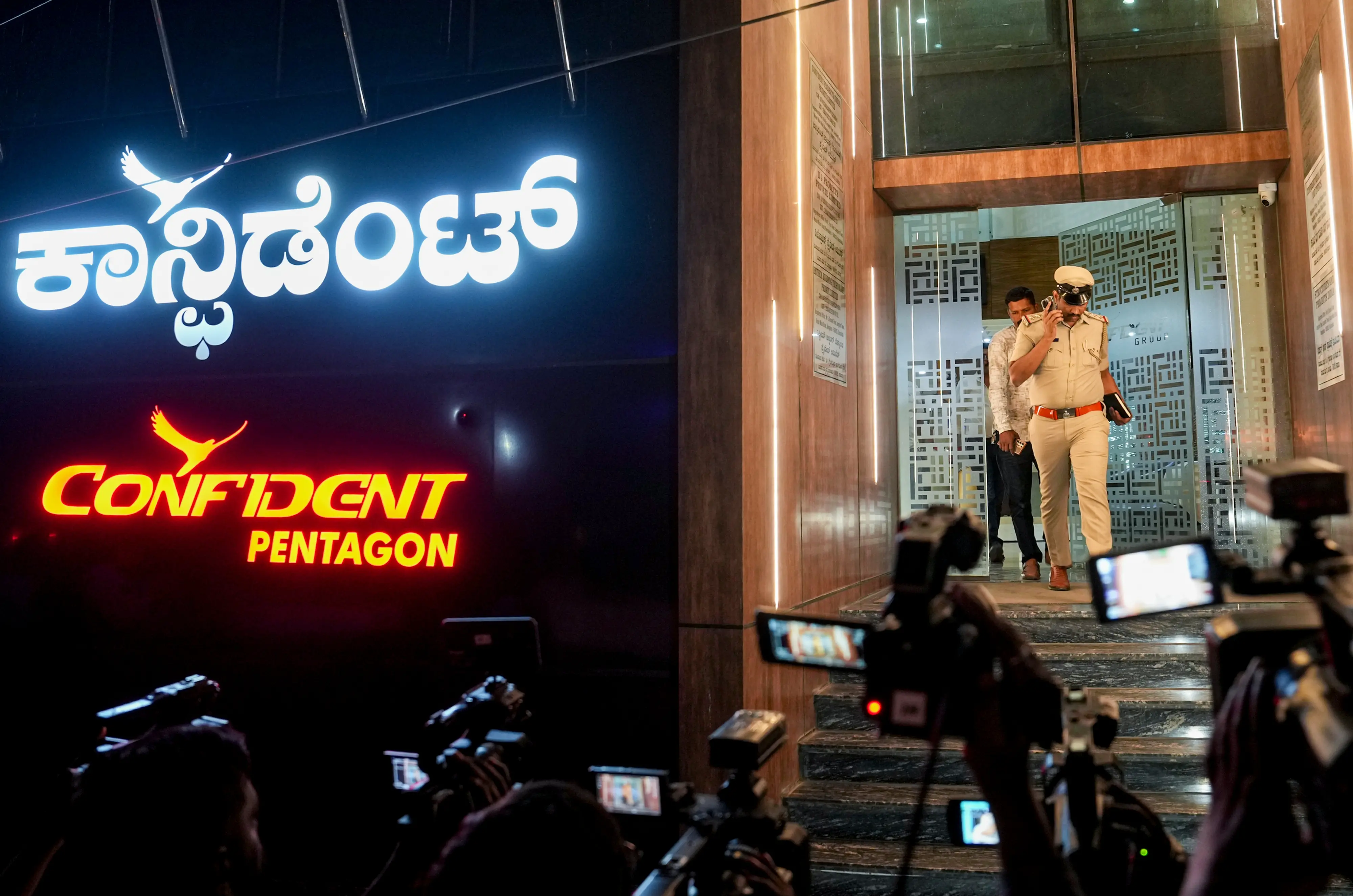 A police official and others exit Confident Group's office building amid investigation after the founder and chairman of the real estate firm C J Roy was found dead in the office, in Bengaluru, Karnataka | PTI