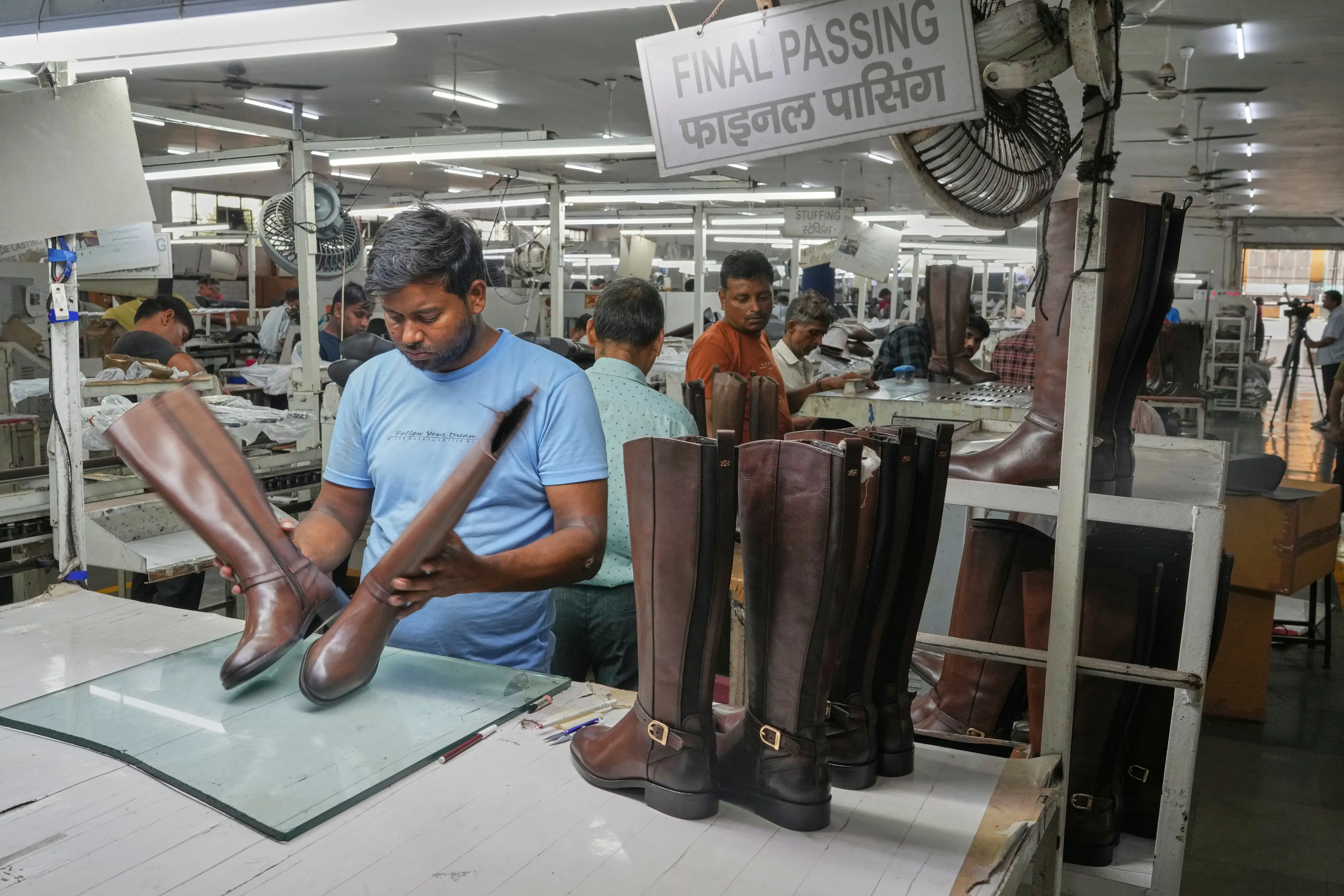 A worker inspects high ankle leather boots before packing in a leather footwear manufacturing unit at Dawar industry in Agra, India | Photo: AP