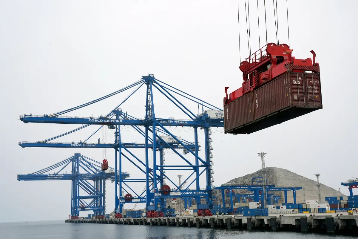 A container is lifted by a crane backdropped by the construction of the Chinese-funded port, in Chancay, Peru | Photo: AP