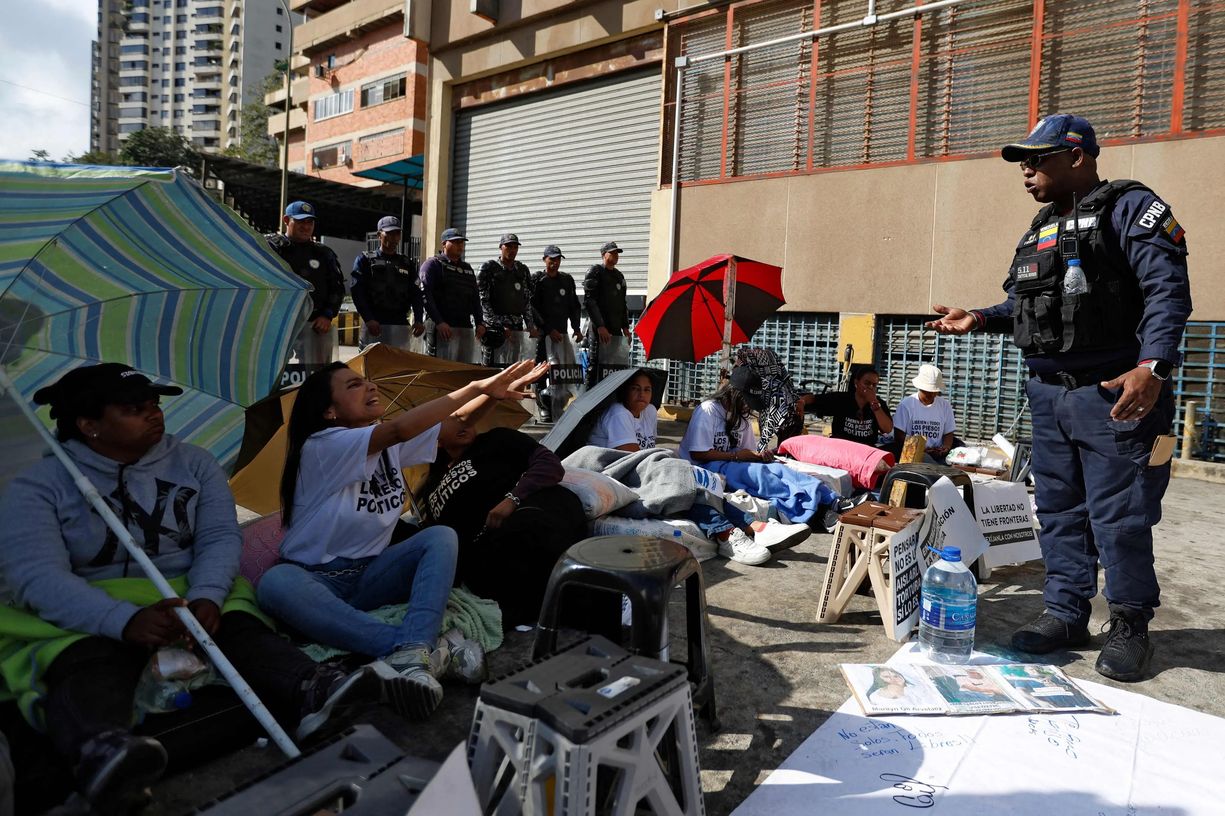 A relative of a political prisoner speaks with a policeman outside the Bolivarian National Police (PNB) Zona 7 prison in Caracas on February 13, 2026 | Photo: AFP