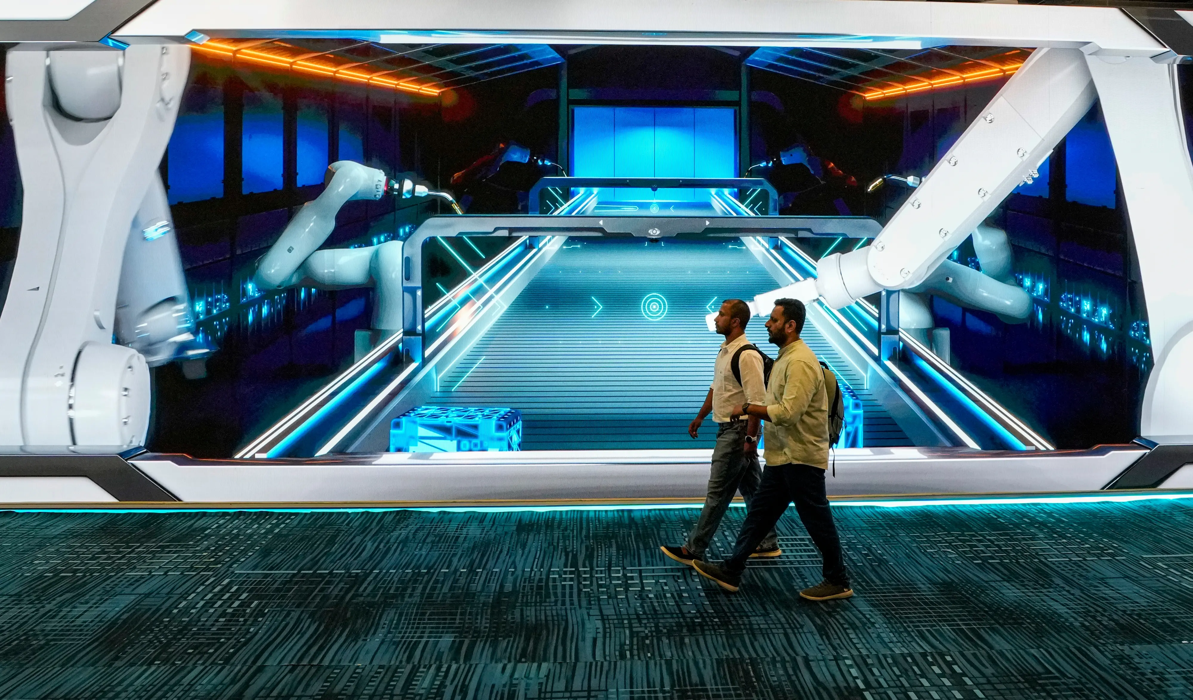 Visitors walk past a large digital installation showcasing robotic automation during the India AI Impact Summit 2026 | Photo: PTI