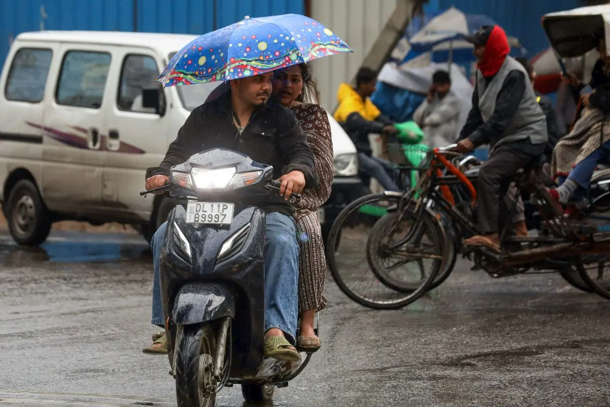 Commuters cover themselves with an umbrella as they ride on a scooter during the rain, in New Delhi on Wednesday. (ANI Photo/Naveen Sharma)