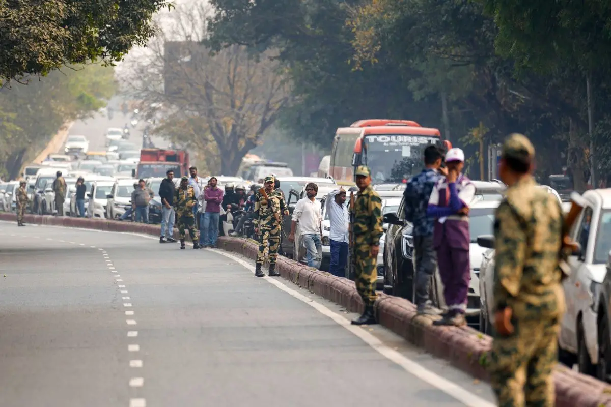 Security personnel keep vigil as commuters are stranded in a traffic jam on Dr Zakir Hussain Marg, near Bharat Mandapam amid the ongoing AI Impact Summit, in New Delhi (Photo: PTI)