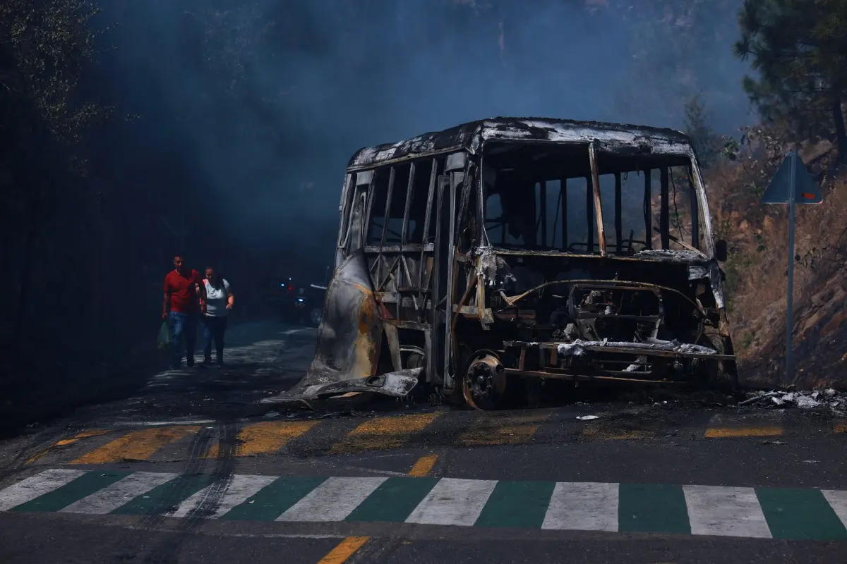 Pedestrians walk past a charred vehicle after it was set on fire, on a road in Cointzio, Michoacán state, Mexico, Sunday, after the death of the leader of the Jalisco New Generation Cartel, Nemesio Rubén Oseguera Cervantes, known as "El Mencho." Photo: AP/PTI