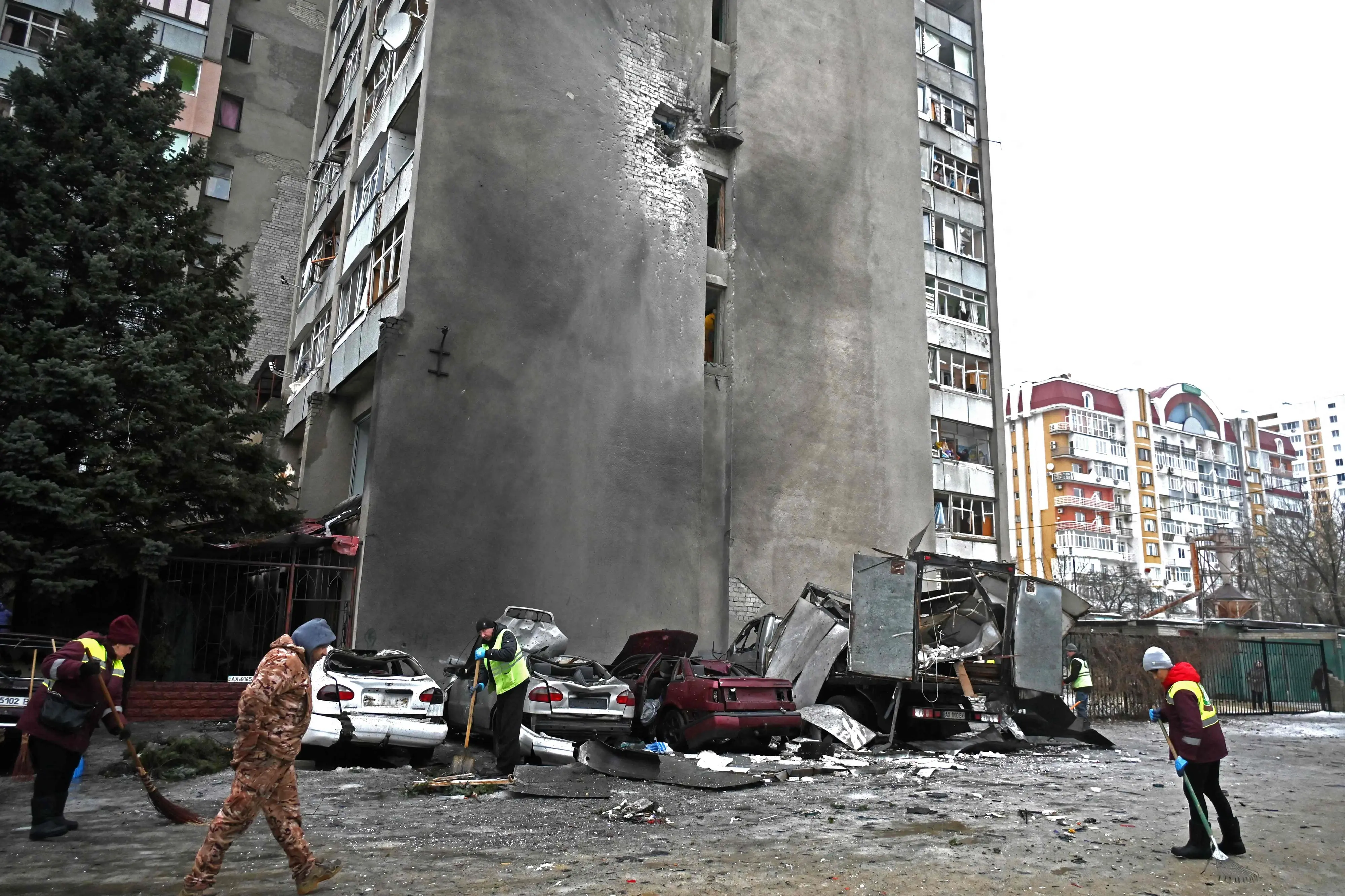 Communal workers clear debris next to destroyed cars in the courtyard of a damaged residential building following an air attack in Kharkiv on February 26, 2026 | Photo: AFP