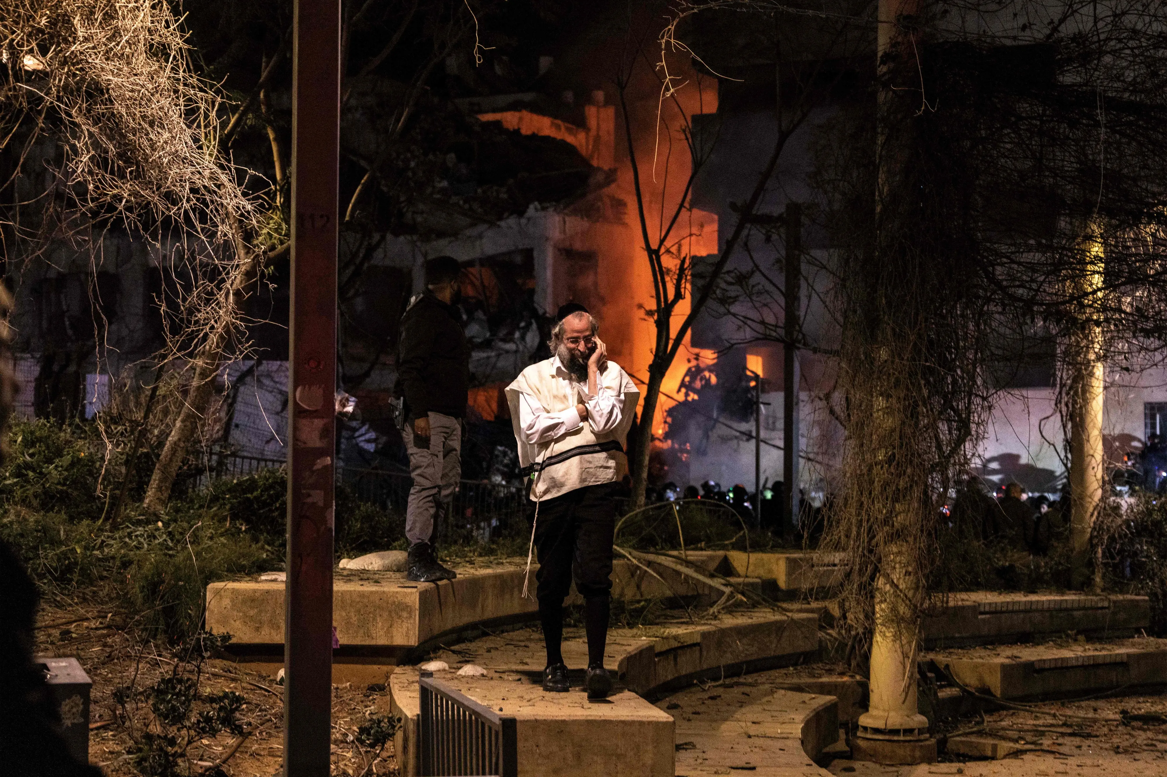 An ultra-orthodox Jewish man speaks on a phone near the site of an Iranian missile strike in Tel Aviv | AFP