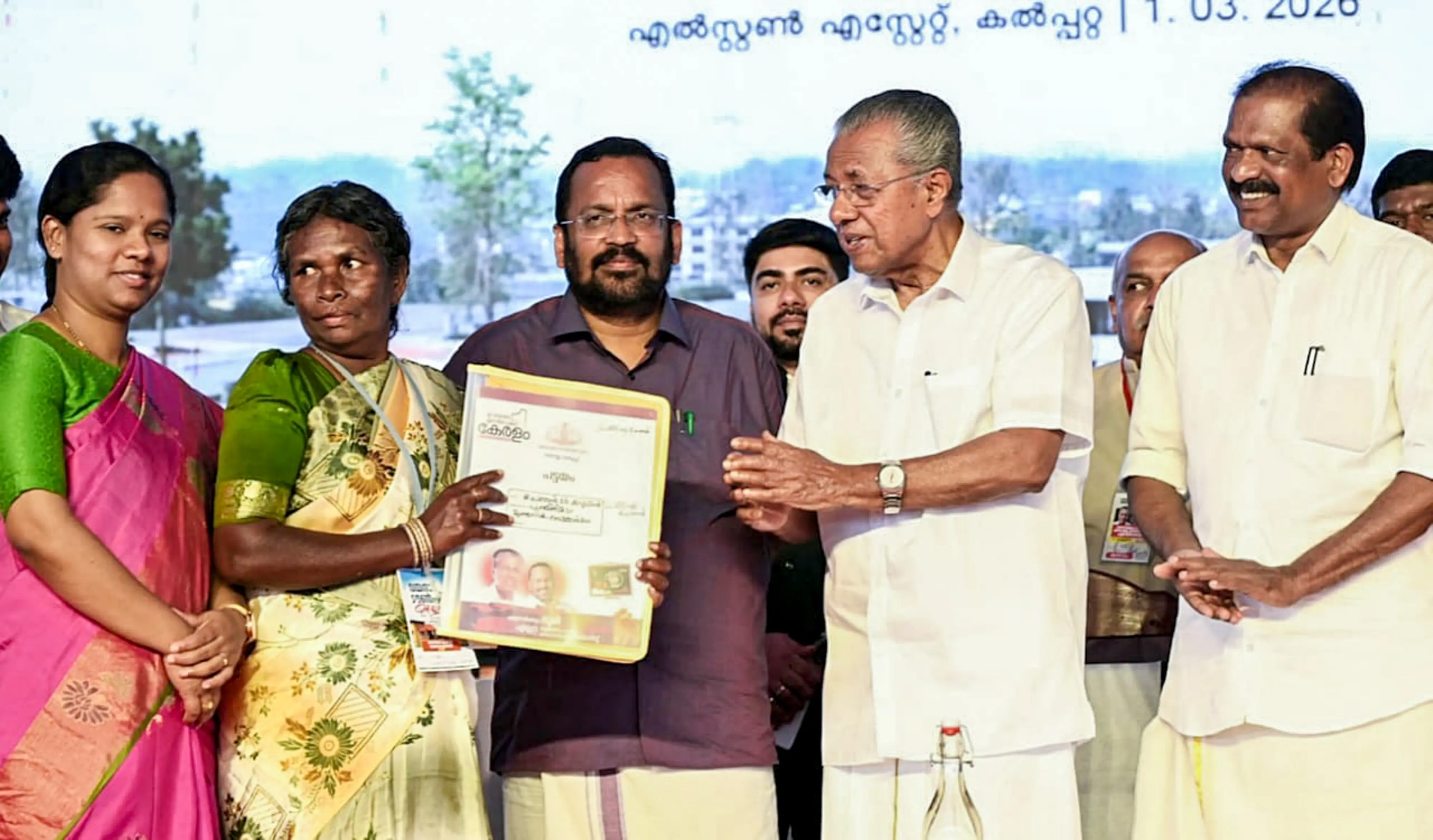 Kerala Chief Minister Pinarayi Vijayan distributes a title deed to a family during the allotment of houses to 178 families in the first phase of the Wayanad Model Township | photo: PTI