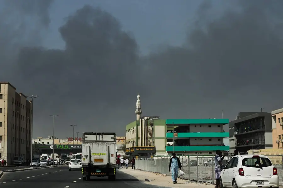 People walk in an area near thick smoke rising from the site of a reported Iranian strike in Dubai
