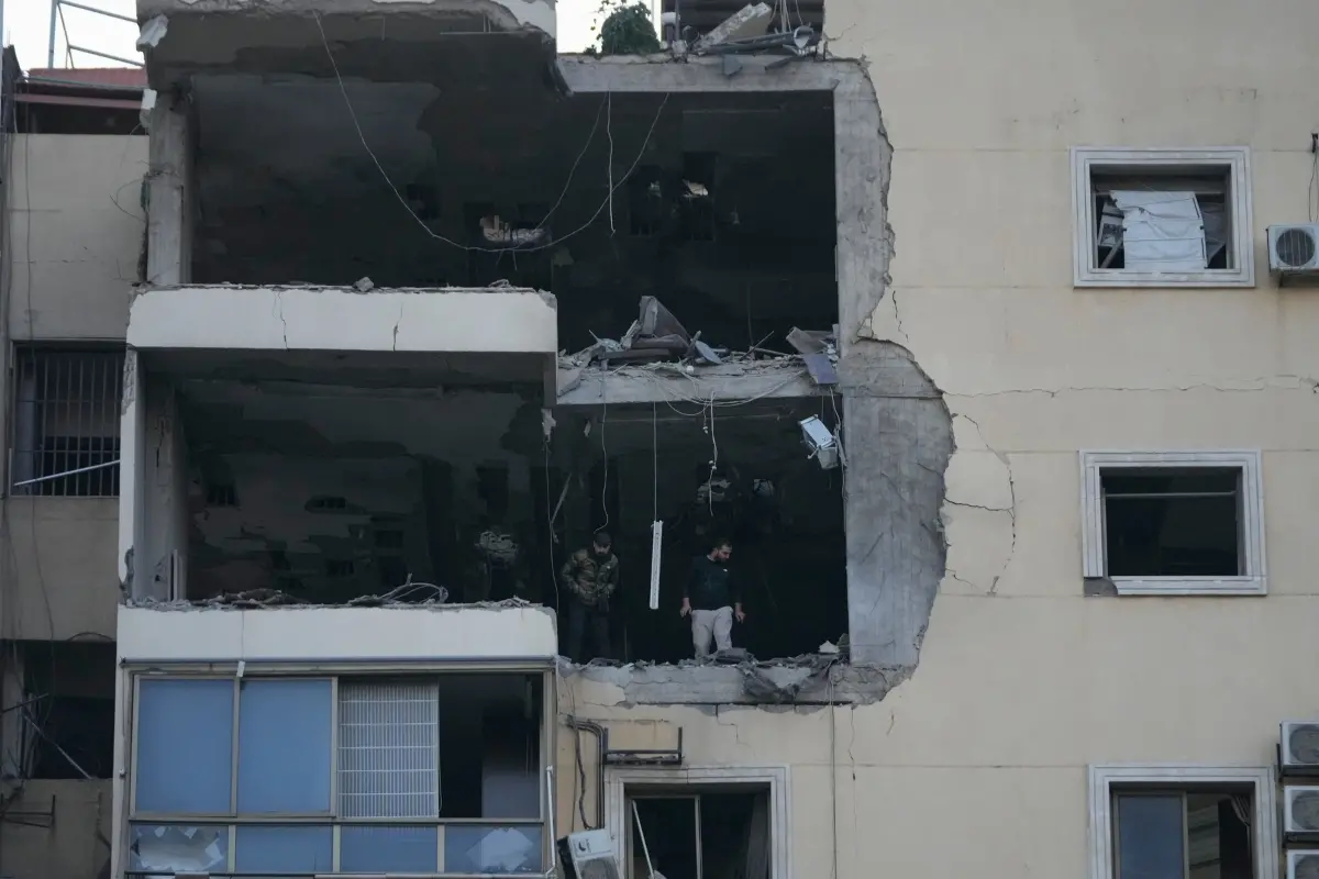 People inspect the damage in an apartment building after it was hit by an Israeli airstrike | Photo: AP