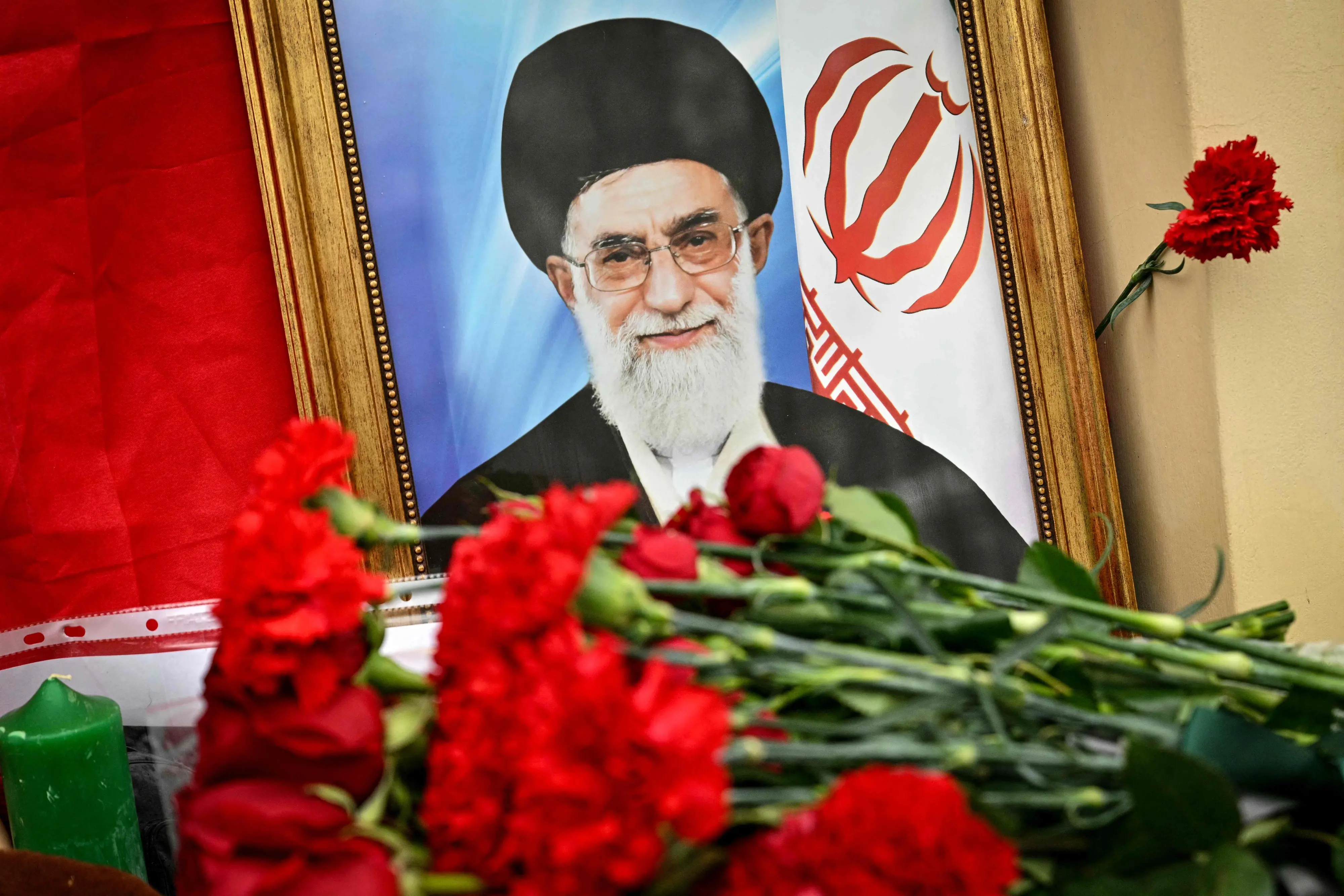 This photograph shows flowers laid at a makeshift altar with a portrait of late Iran's supreme leader Ayatollah Ali Khamenei and a flag of the Islamic Republic of Iran outside the Iranian Embassy in Russia | AFP
