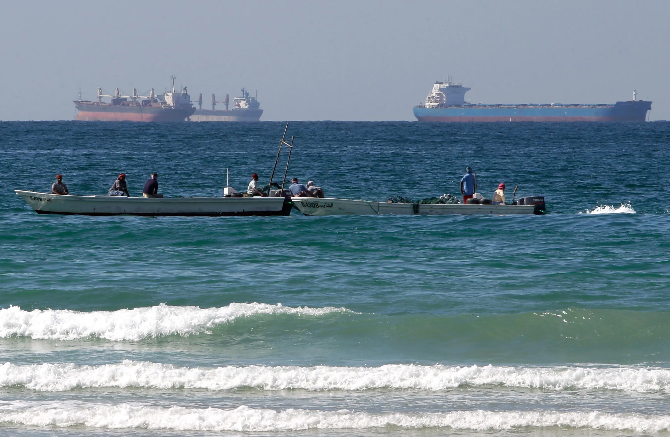 Fishermen work in front of oil tankers south of the Strait of Hormuz | AP