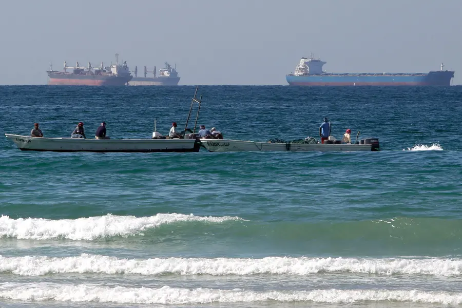 Fishermen work in front of oil tankers south of the Strait of Hormuz