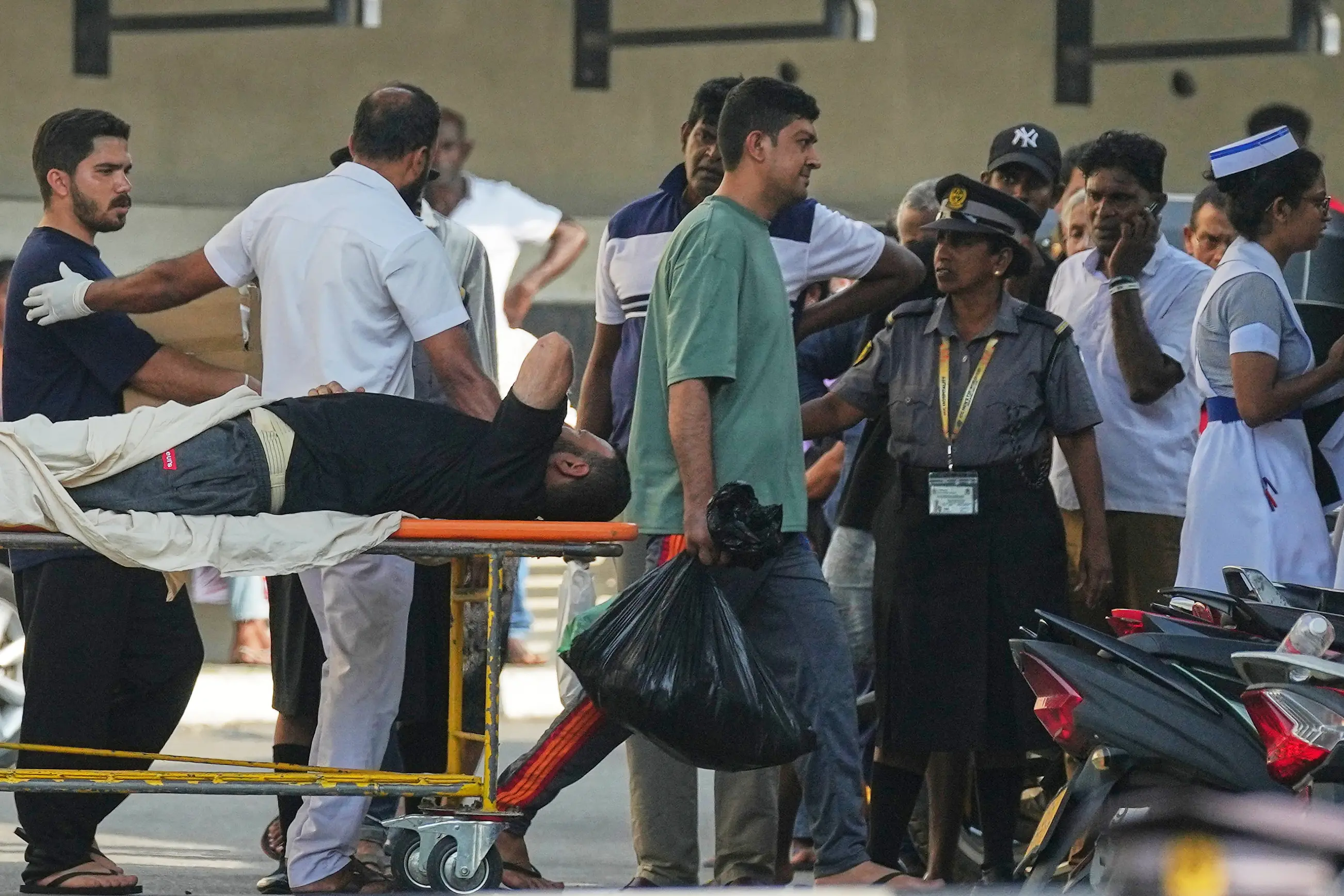 Iranian sailors, one on a gurney and the other in a green t-shirt, who were rescued from IRIS Dena warship by Sri Lanka's navy, are escorted to a Judicial Medical Officer from the National Hospital, in Galle, Sri Lanka | Photo: AP