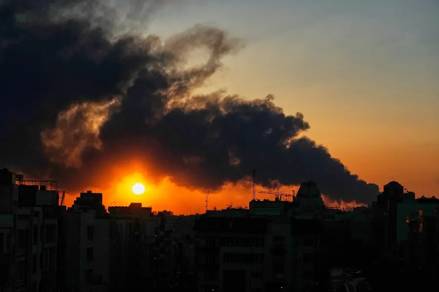 The sun sets behind a plume of smoke rising from a U.S.–Israeli military strike in Tehran