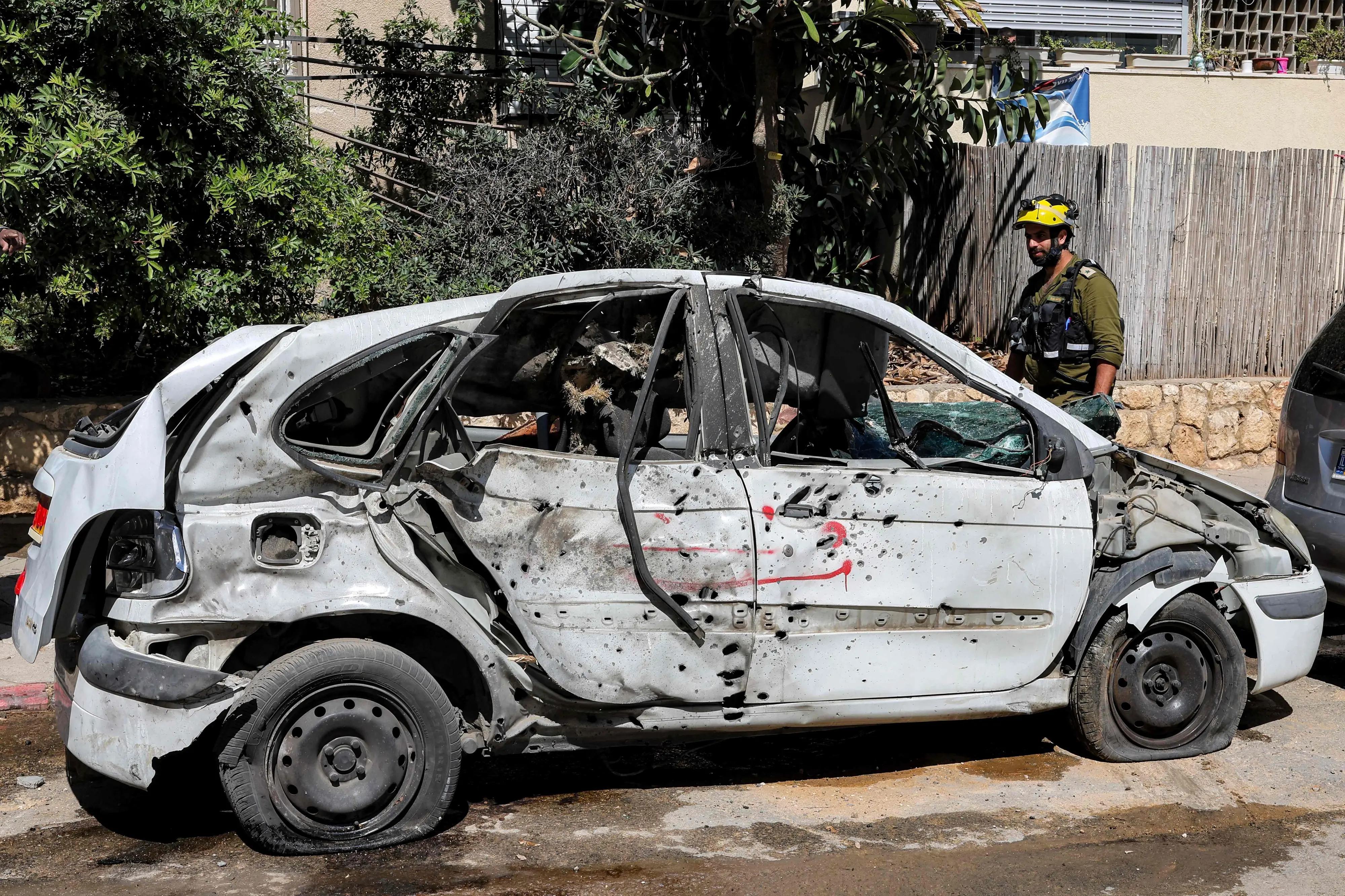 Israeli security forces and first responders gather by a destroyed vehicle at the site of an Iranian strike that hit a residential neighbourhood in Bat Yam, south of Tel Aviv | AFP