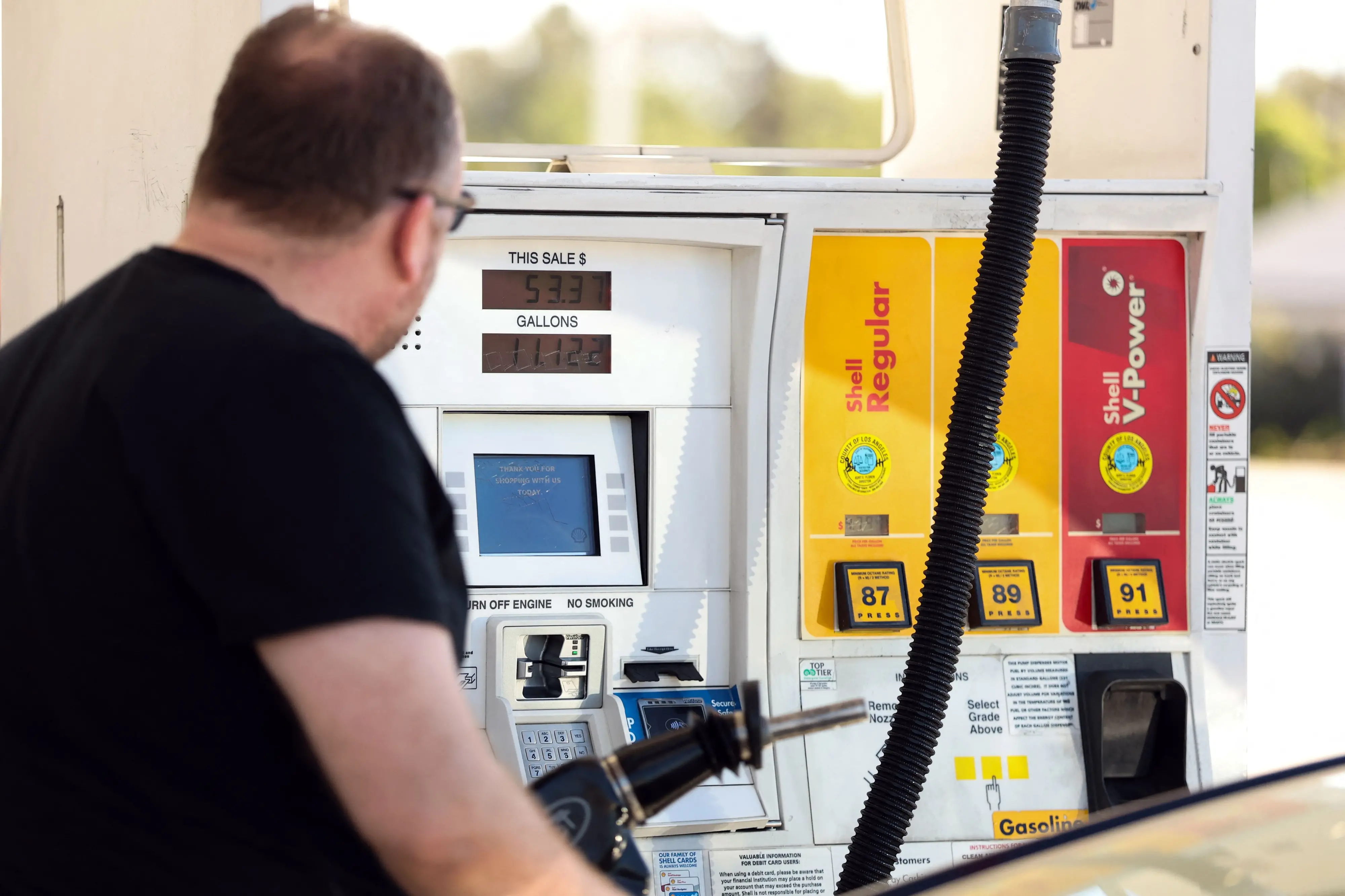 A man pumps gasoline into his vehicle at a gas station in Los Angeles, California | AFP
