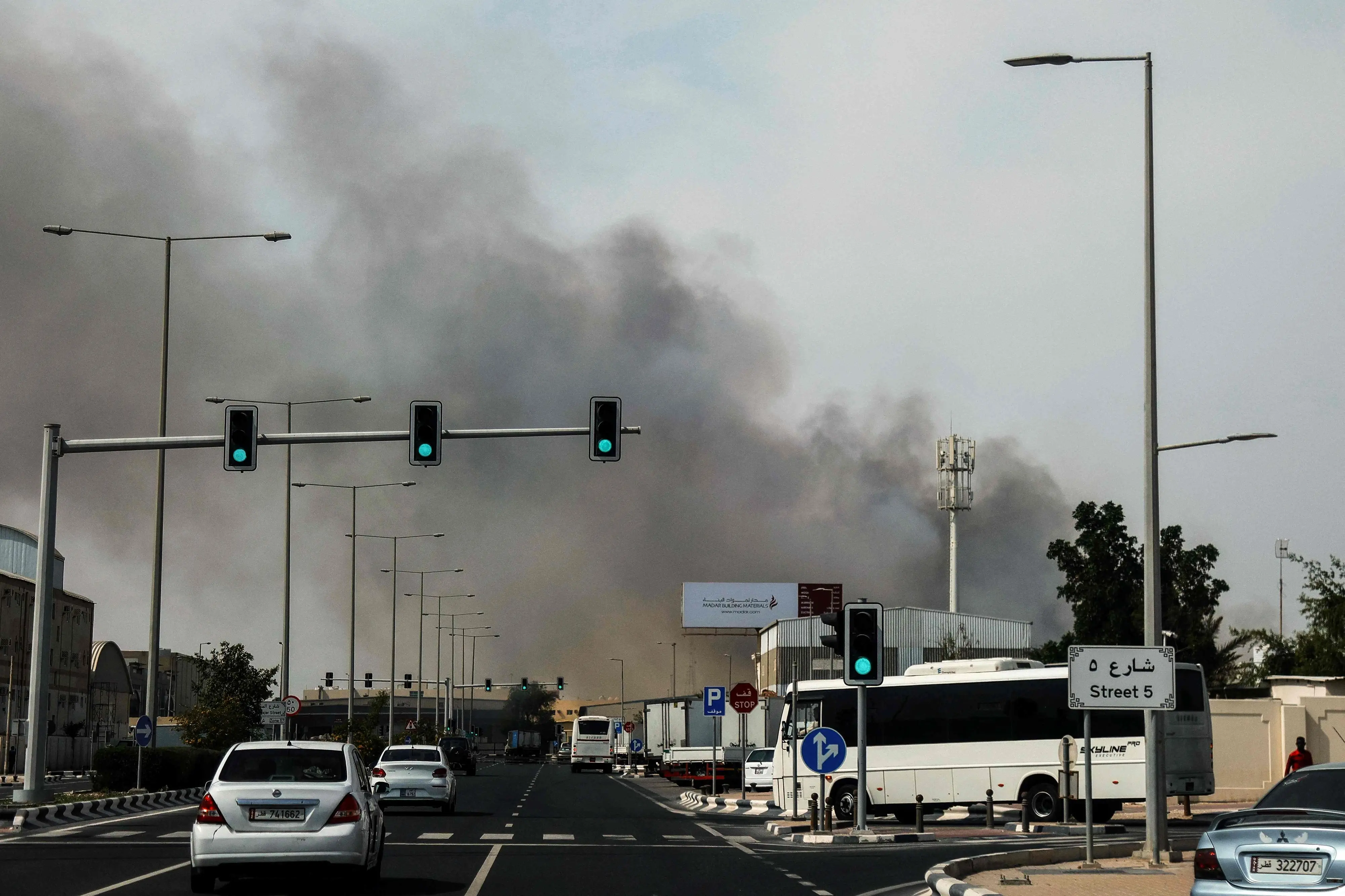 Motorists drive past a plume of smoke rising from a reported Iranian strike in the industrial district of Doha on March 1, 2026 (Photo: AFP)