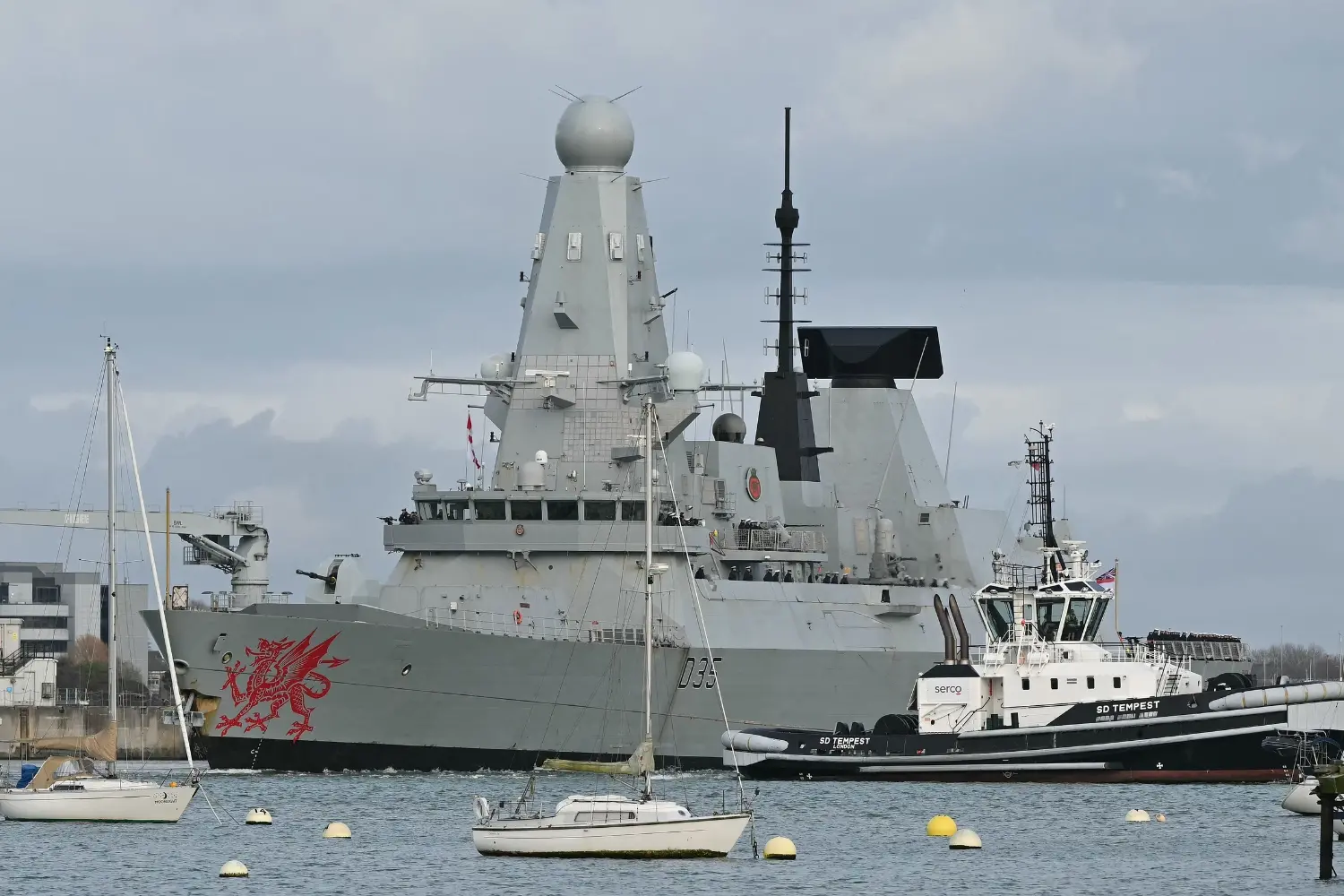 HMS Dragon, a Royal Navy Type 45 Daring-class air-defence destroyer warship, is guided by tug boats operated by Serco Marine Services, as it departs from HM Naval Base Portsmouth, on the south coast of England. | Photo: AFP