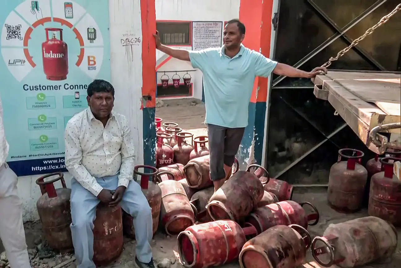 A man stands on an LPG cylinder at a gas agency amid the reports of LPG supply shortage in the country, in New Delhi on Saturday. (ANI Video Grab)