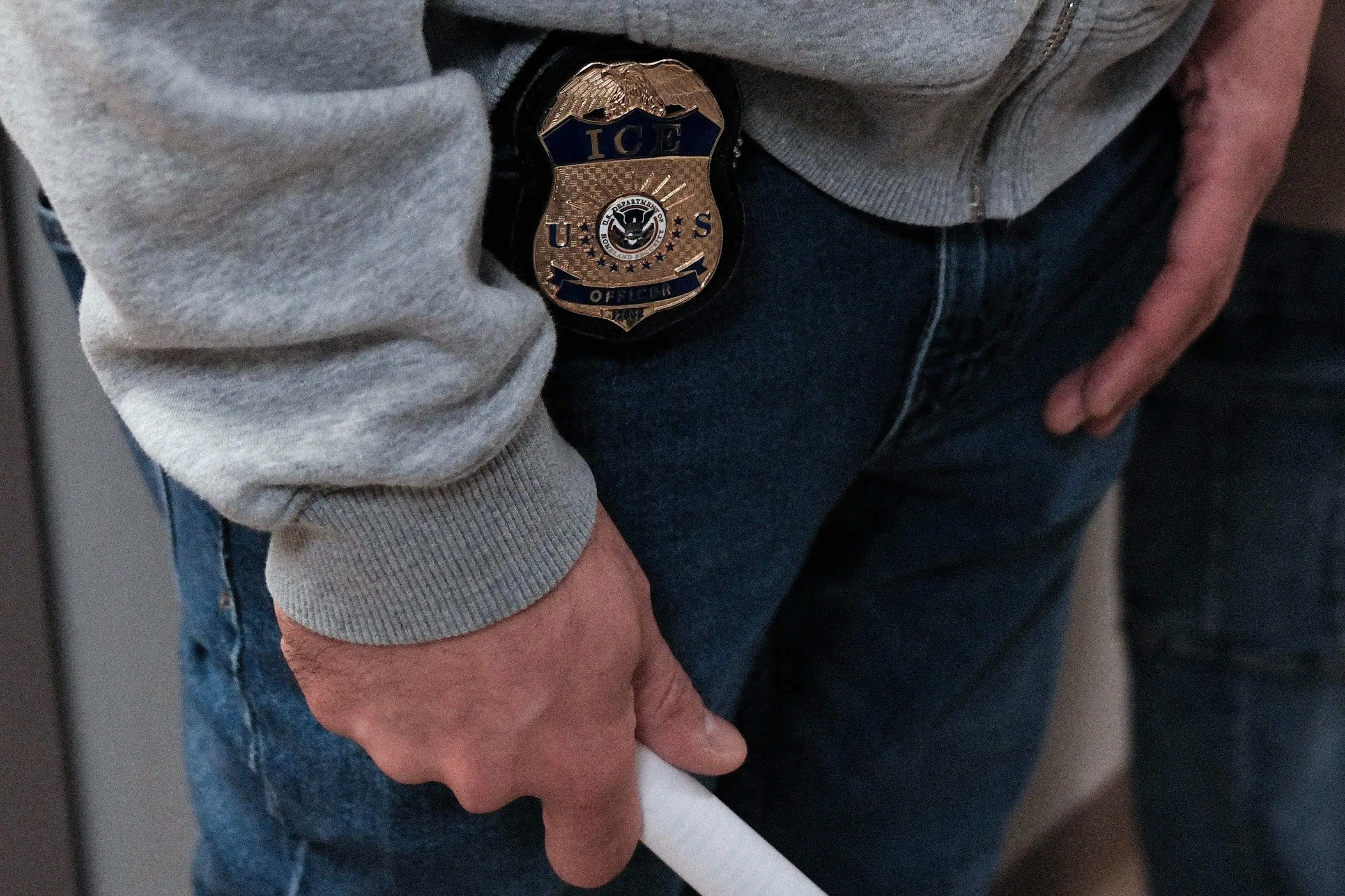 A ICE shield is seen at the belt of a federal agent as he stands in a hallway at the New York Federal Plaza Immigration Court inside the Jacob K. Javitz Federal Building in New York  | AFP