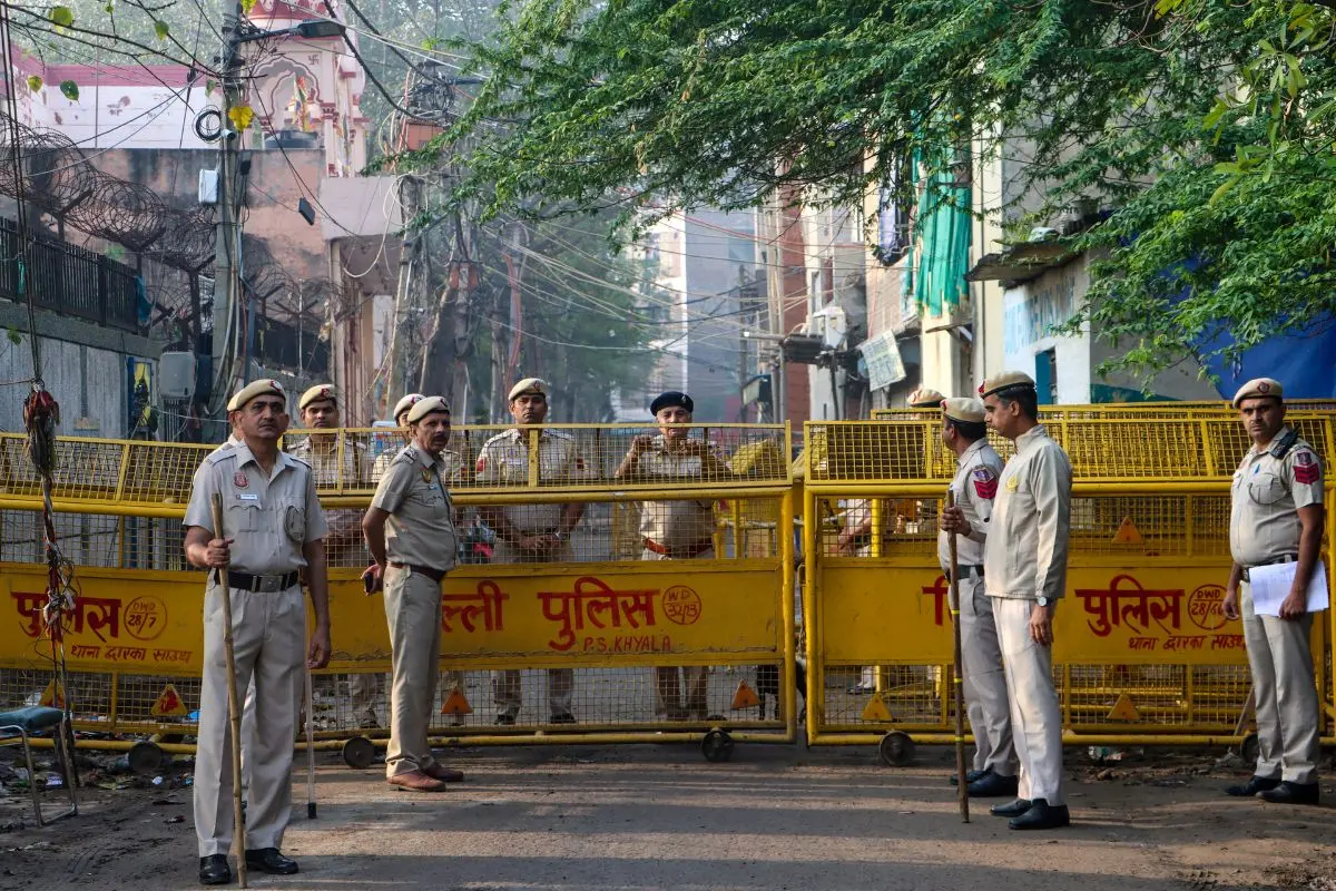 Police personnel stand guard as people arrive to offer Eid al-Fitr prayers in Uttam Nagar, New Delhi, on Saturday, March 21, 2026, where the festival is being observed under tight security following a recent clash that left one person dead and triggered communal tensions. (PTI Photo)