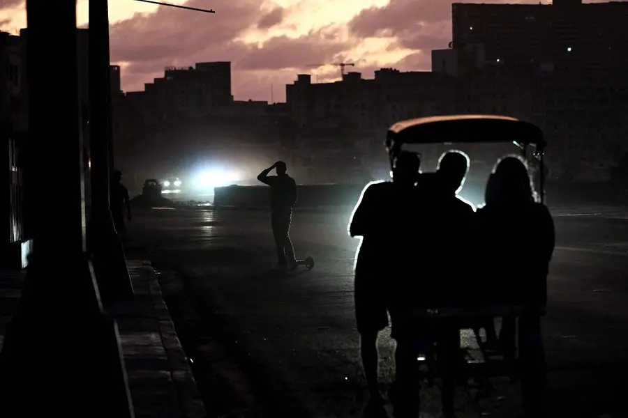 People transit on a street without power during a nation wide blackout in Havana