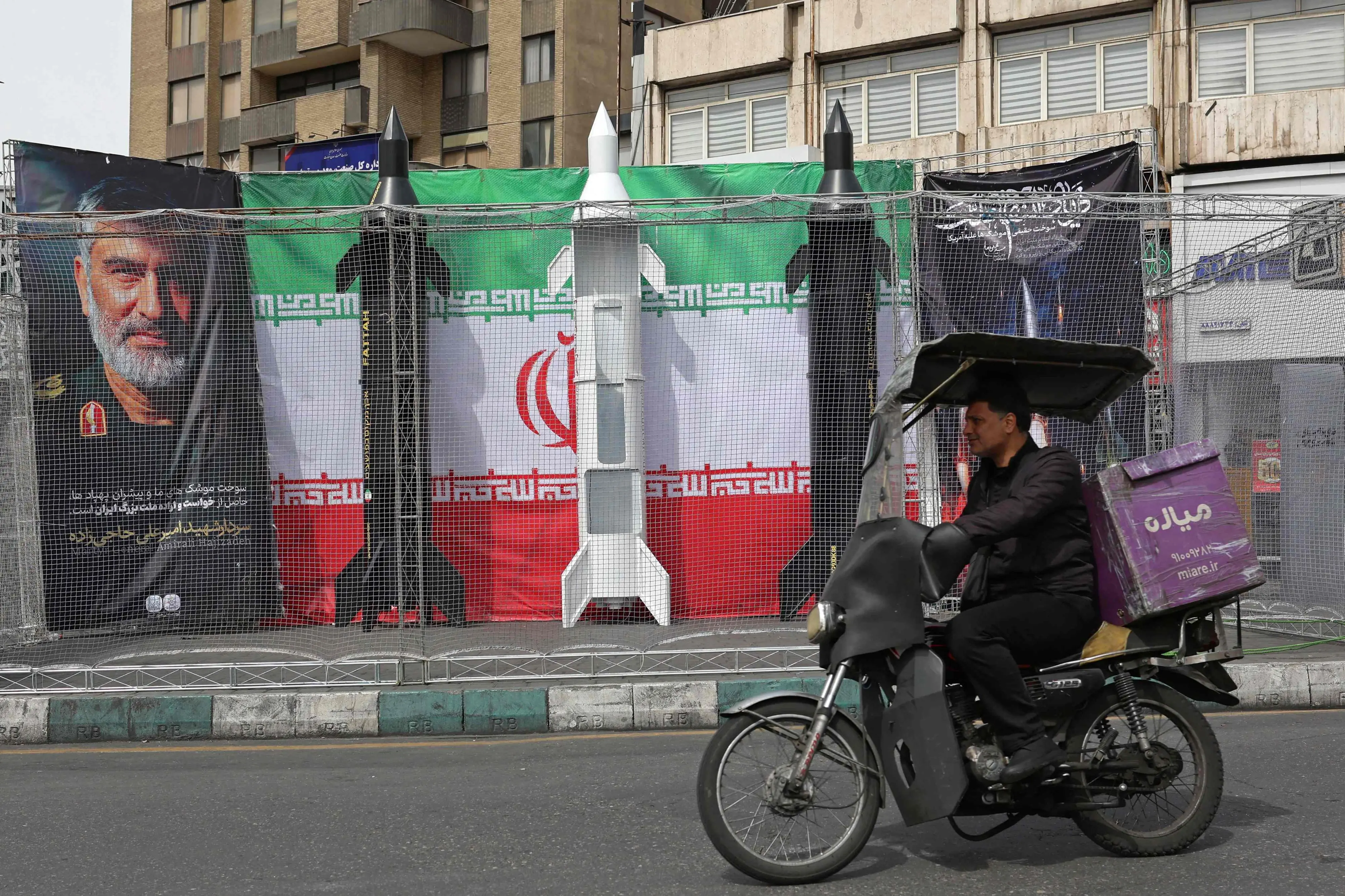 A motorist rides past the dummy models of Iranian missiles installed along the roadside at Valiasr Square in Tehran | AFP