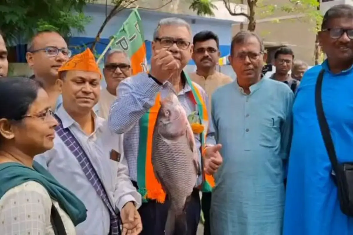 BJP candidate Dr Sharadwat Mukhopadhyay holds up a large catla fish while campaigning in Bidhannagar, turning the poll trail into a viral, tongue-in-cheek rebuttal to 'non-veg ban' claims. Screengrab: X@KhelaHobePart2