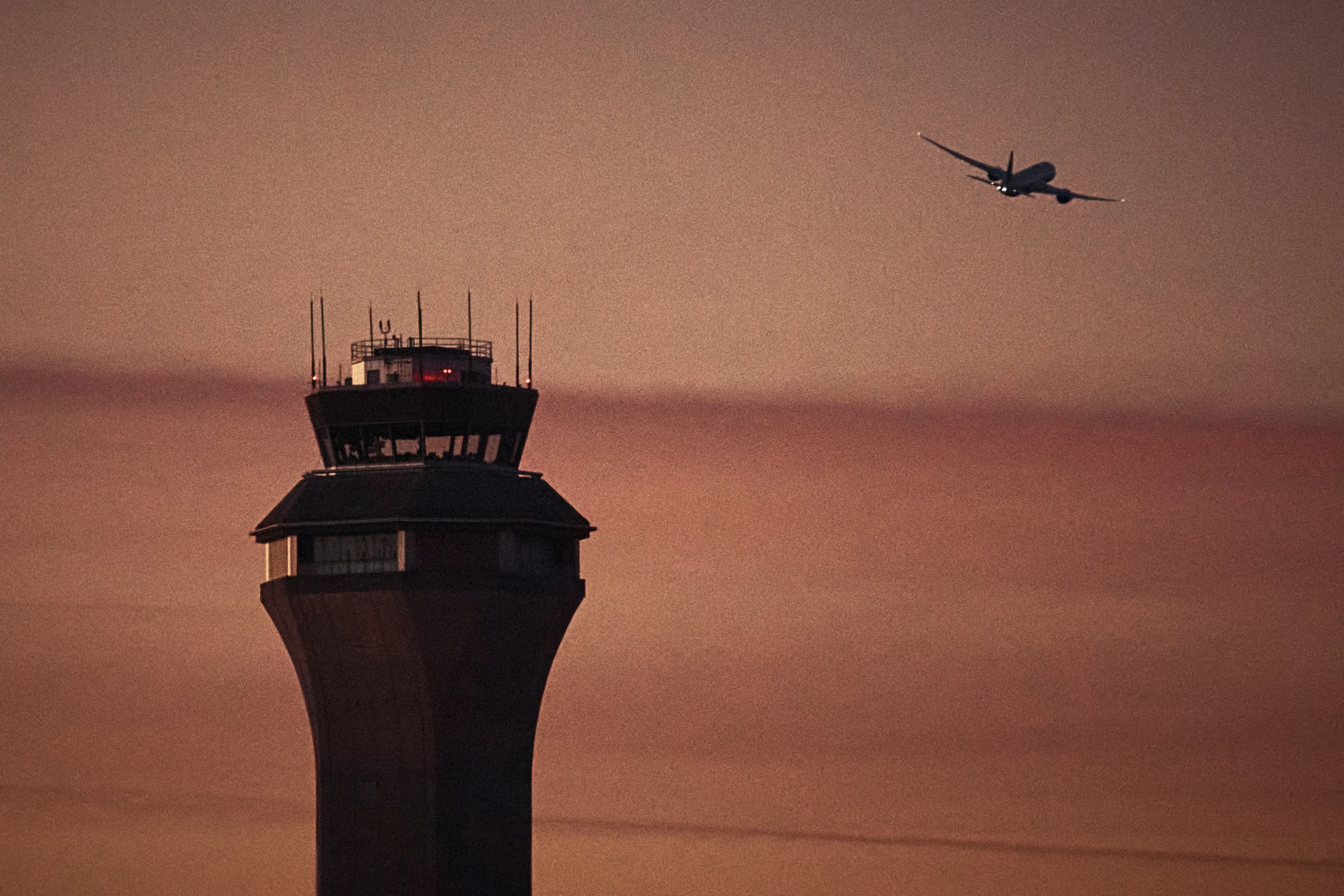 A plane flies by a control tower at Newark Liberty International Airport (AP Photo/Andres Kudacki, File)