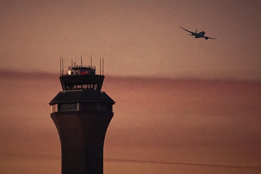 A plane flies by a control tower at Newark Liberty International Airport