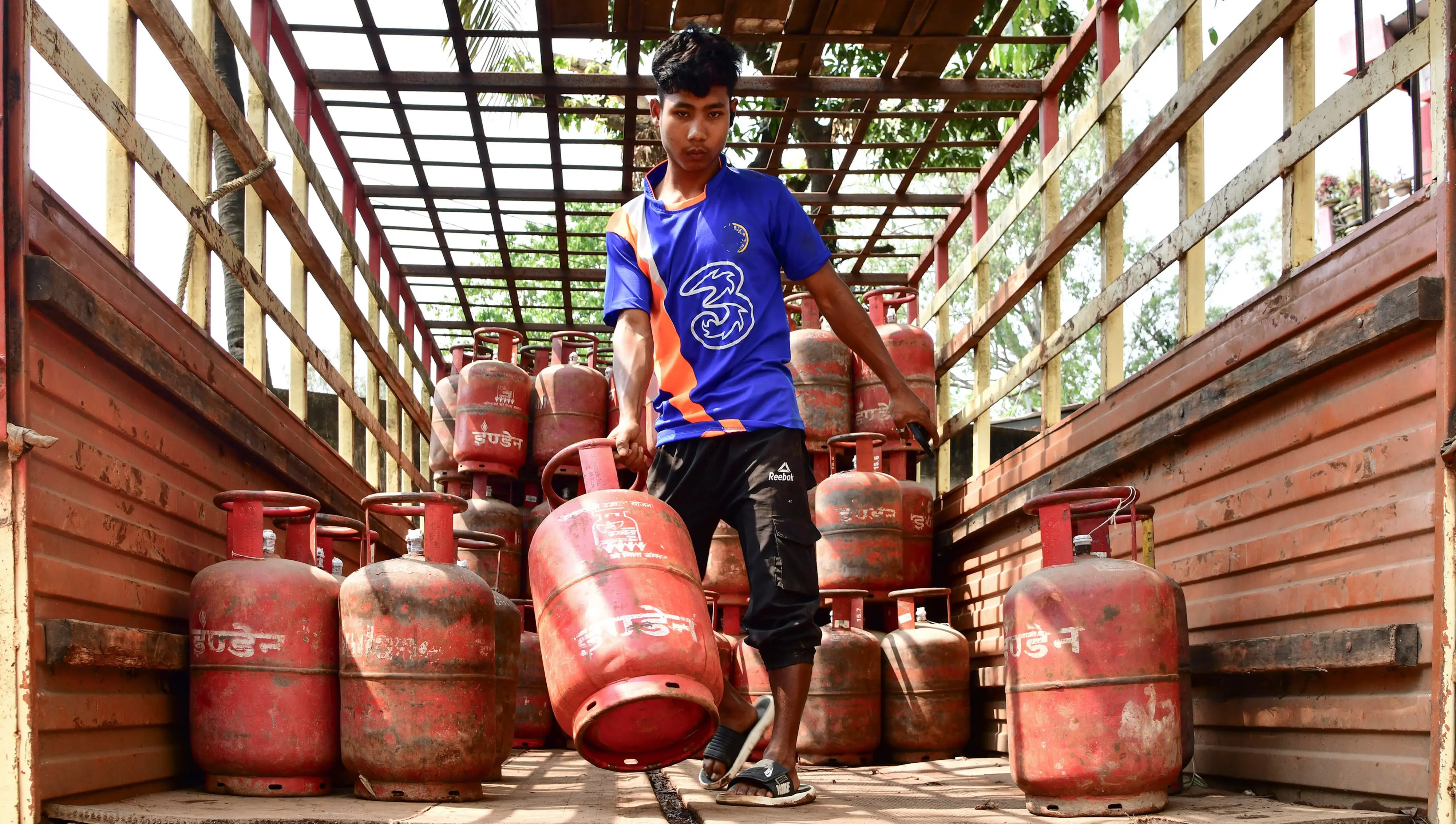 A worker unloads LPG cylinders to distribute| Photo: PTI
