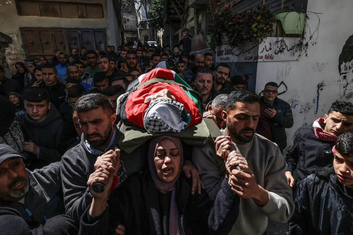 Mother of a 15-year-old Palestinian who was killed by Israeli security forces during a military raid in the al-Dheisheh refugee camp near the occupied West Bank city of Bethlehem, carries her son's body during his funeral.| Photo: AFP