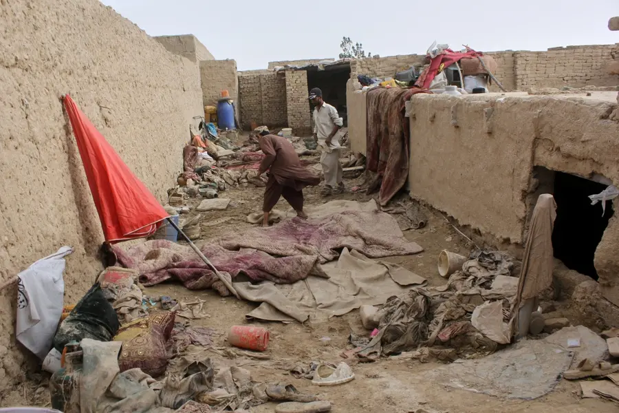 Locals inspect a damaged house following floods, landslides and thunderstorms in Afghanistan