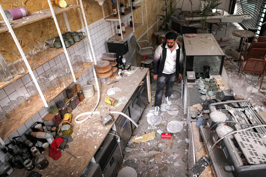 Cafe staff inspect the destruction at the premises following a missile strike on their building earlier in the day in Tehra