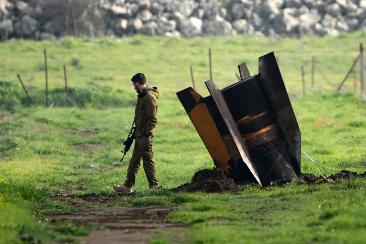 An Israeli soldier stands next to a fragment of a missile fired from Iran and intercepted by Israeli air defense system embedded in an open field in the Israeli-controlled Golan Heights. Photo: AP Photo/Ohad Zwigenberg