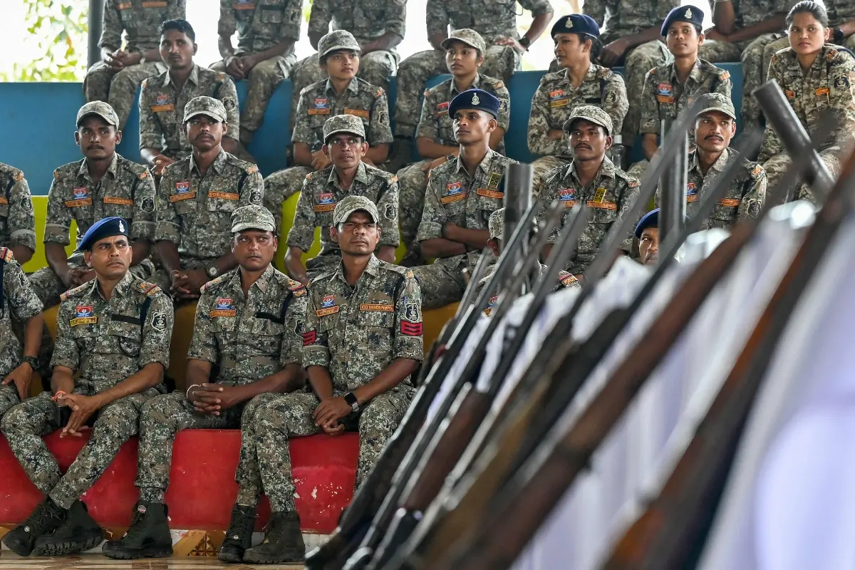 File: Security personnel sit next to weapons seized from Maoist rebels and fighters upon their surrender | Photo: AFP