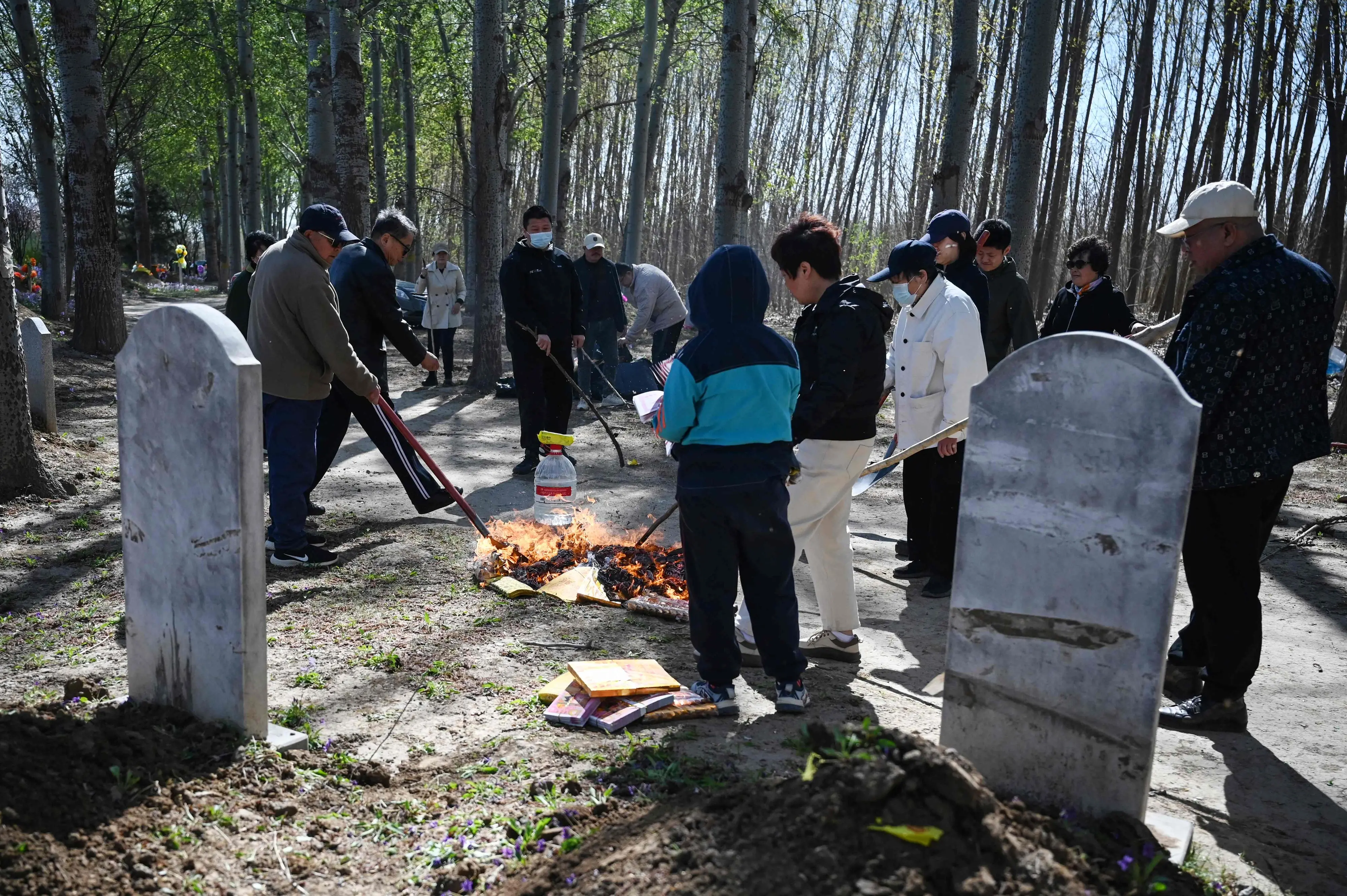 Family members burn paper as they pay their respects at the grave of their ancestor during the annual tomb-sweeping festival | Photo: AFP