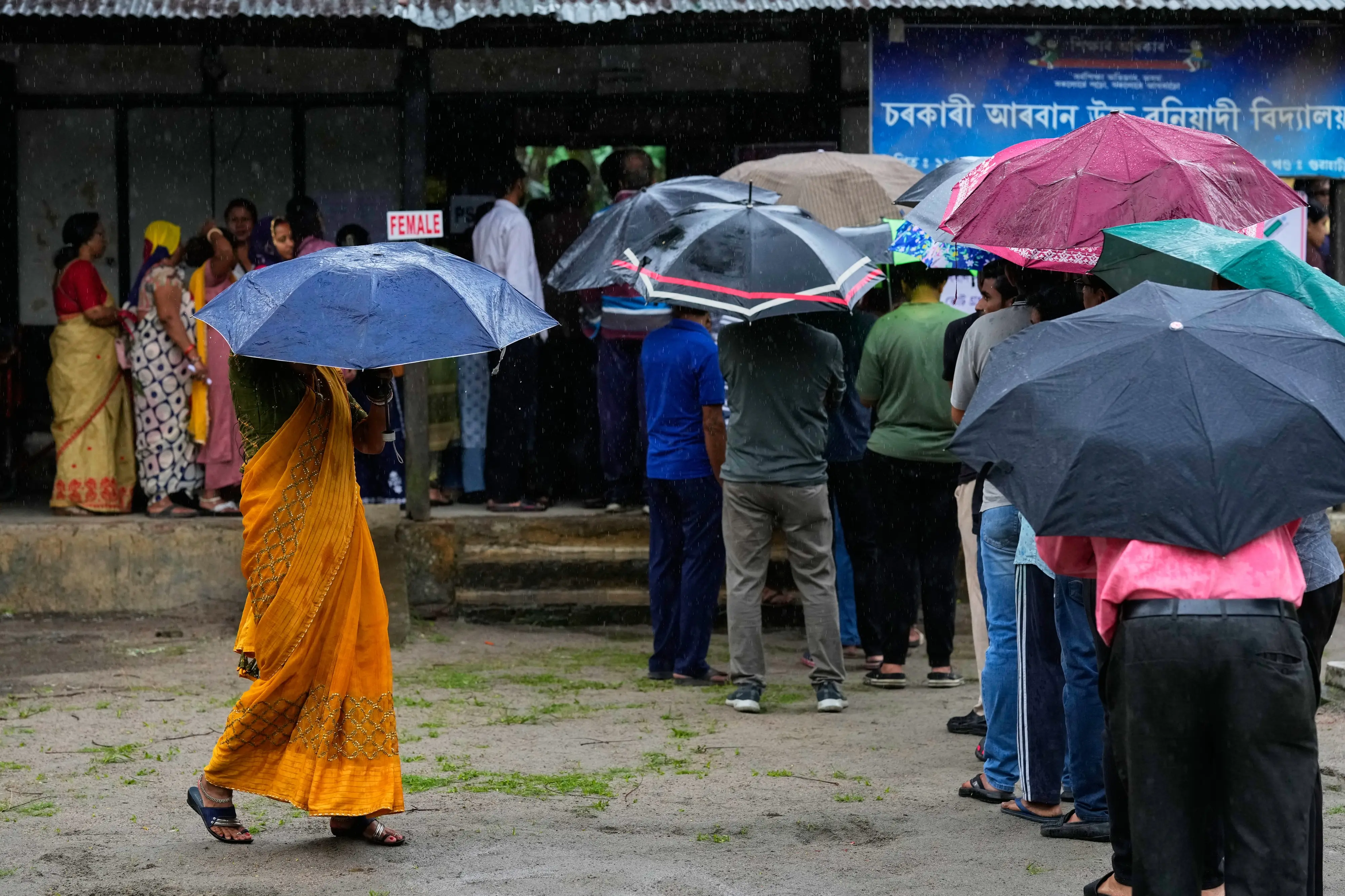 People stand in queue to cast their votes at a polling centre during the Assam state election in Guwahati | AP