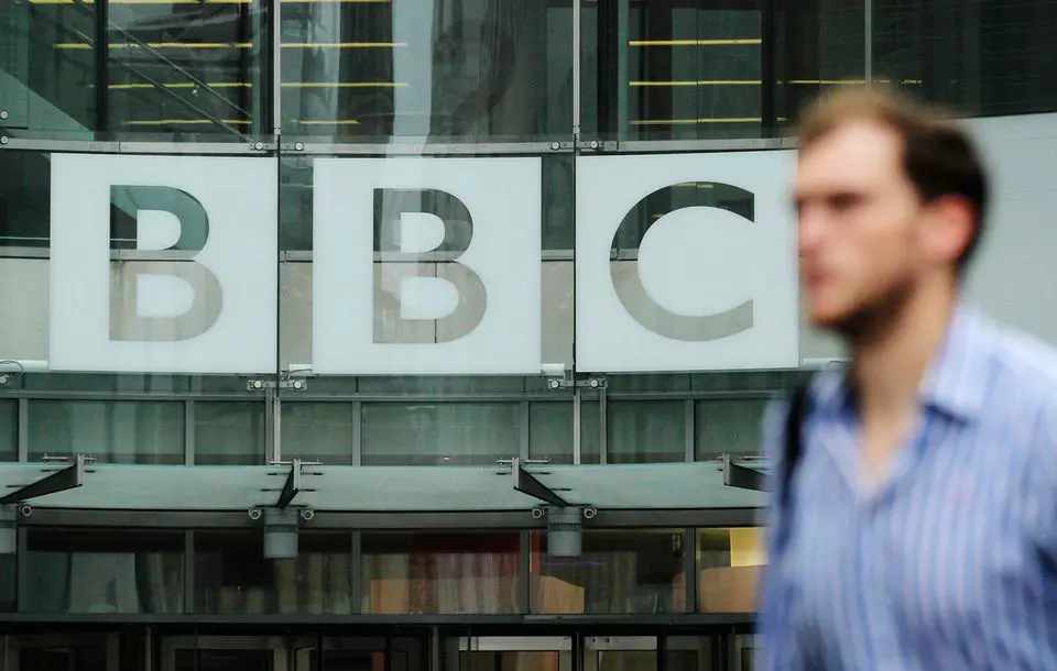 A pedestrian walks past a BBC logo at Broadcasting House in central London | Reuters/Olivia Harris