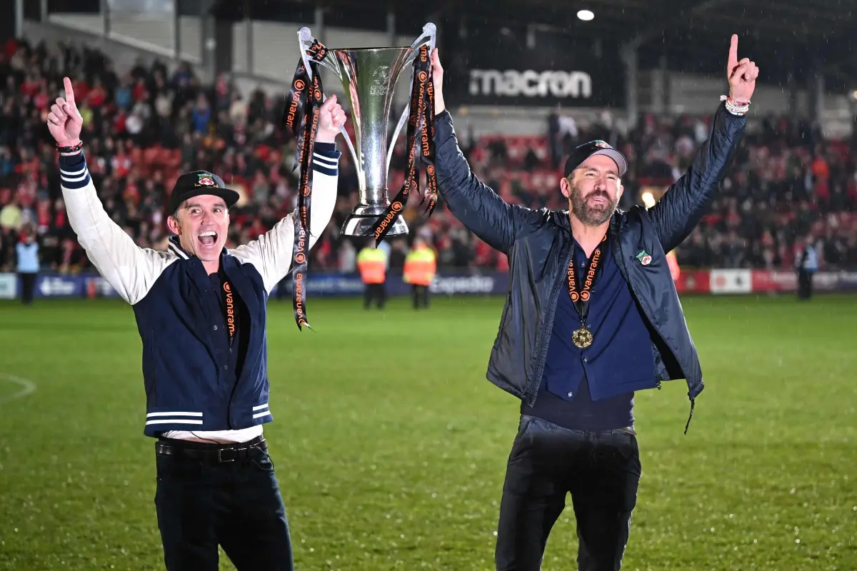 US actor and Wrexham owner Rob McElhenney (L) and US actor and Wrexham owner Ryan Reynolds (R) celebrate on the pitch with the National League trophy after the English National League football match between Wrexham and Boreham Wood at the Racecourse Ground Stadium in Wrexham, north Wales. | File Photo: AFP
