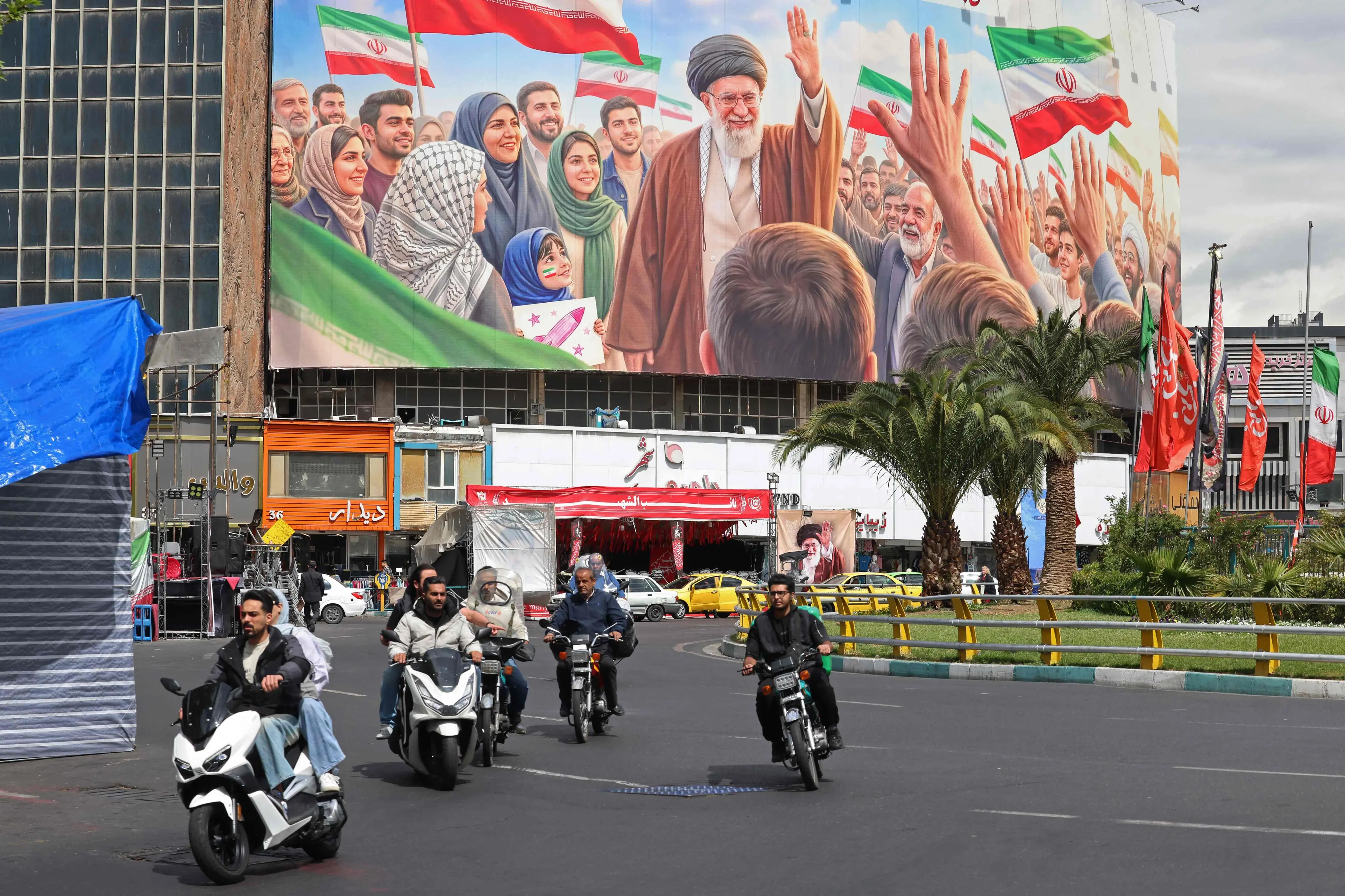 Motorists ride past a giant billboard of slain Iranian supreme leader Ayatollah Ali Khamenei at the Valiasr Square in Tehran on April 19, 2026 | AFP