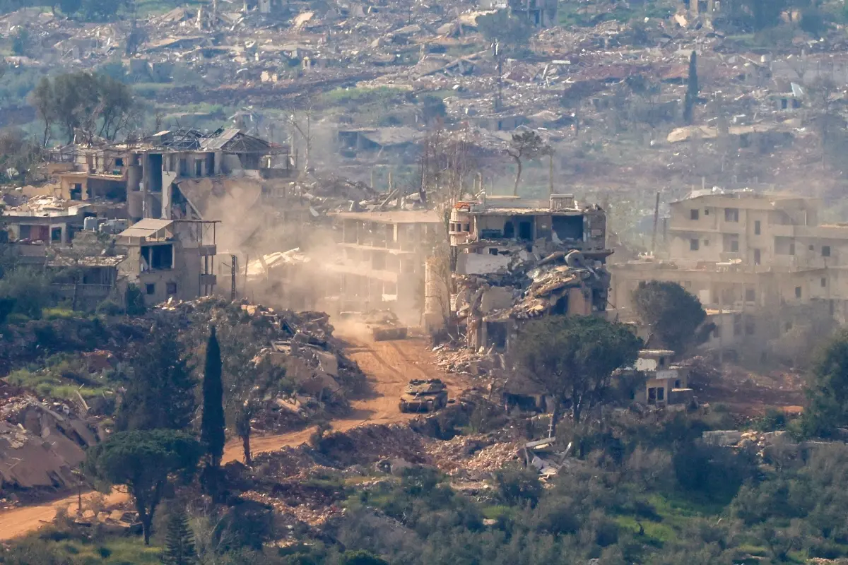 This photograph taken from the northern Israel shows Israeli tanks and military vehicles driving along the road between destroyed houses in southern Lebanon near the border with Israel, on April 25, 2026